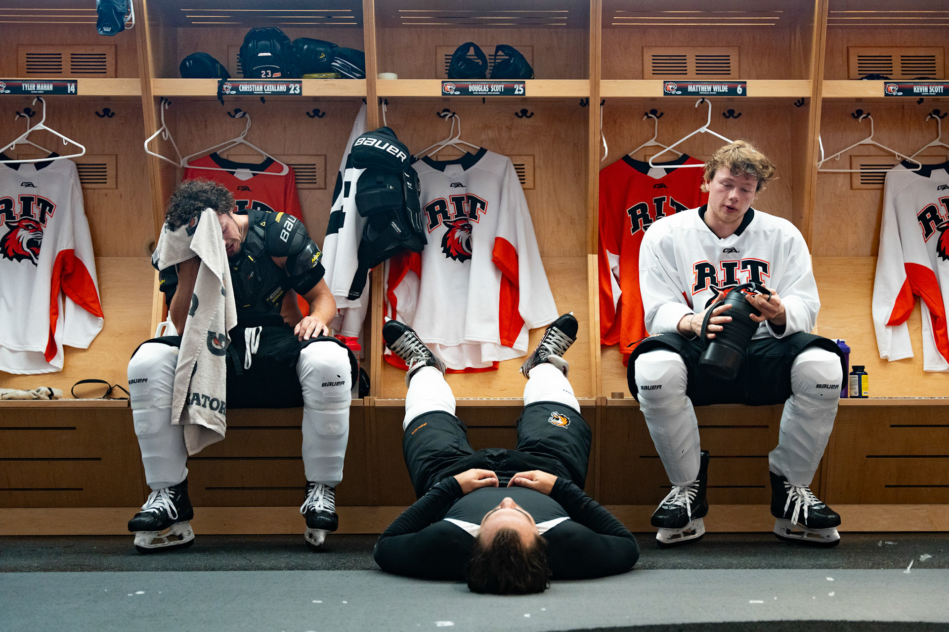Christian Catalano, left, Doug Scott, center, and Matthew Wilde, right, relax after playing in the first period of an RIT men’s hockey team scrimmage in the locker room of the Gene Polisseni Center, Sept. 6, 2023, in Henrietta, N.Y.