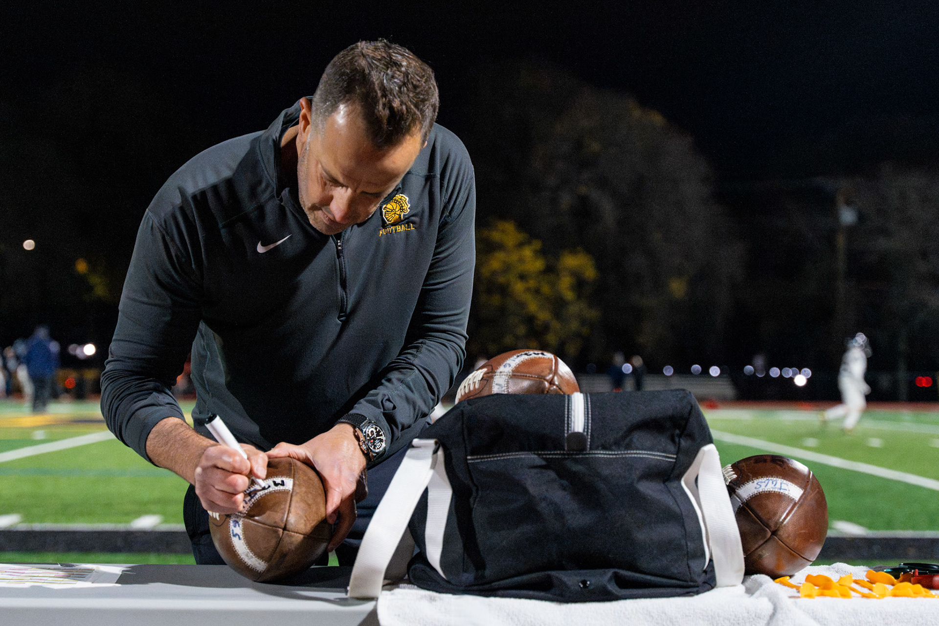 Anthony DiMarco, a father of a player, prepares game balls for the McQuaid Jesuit High School football sectional playoff game against Pittsford High School, Nov. 1, 2024, in Brighton, N.Y.