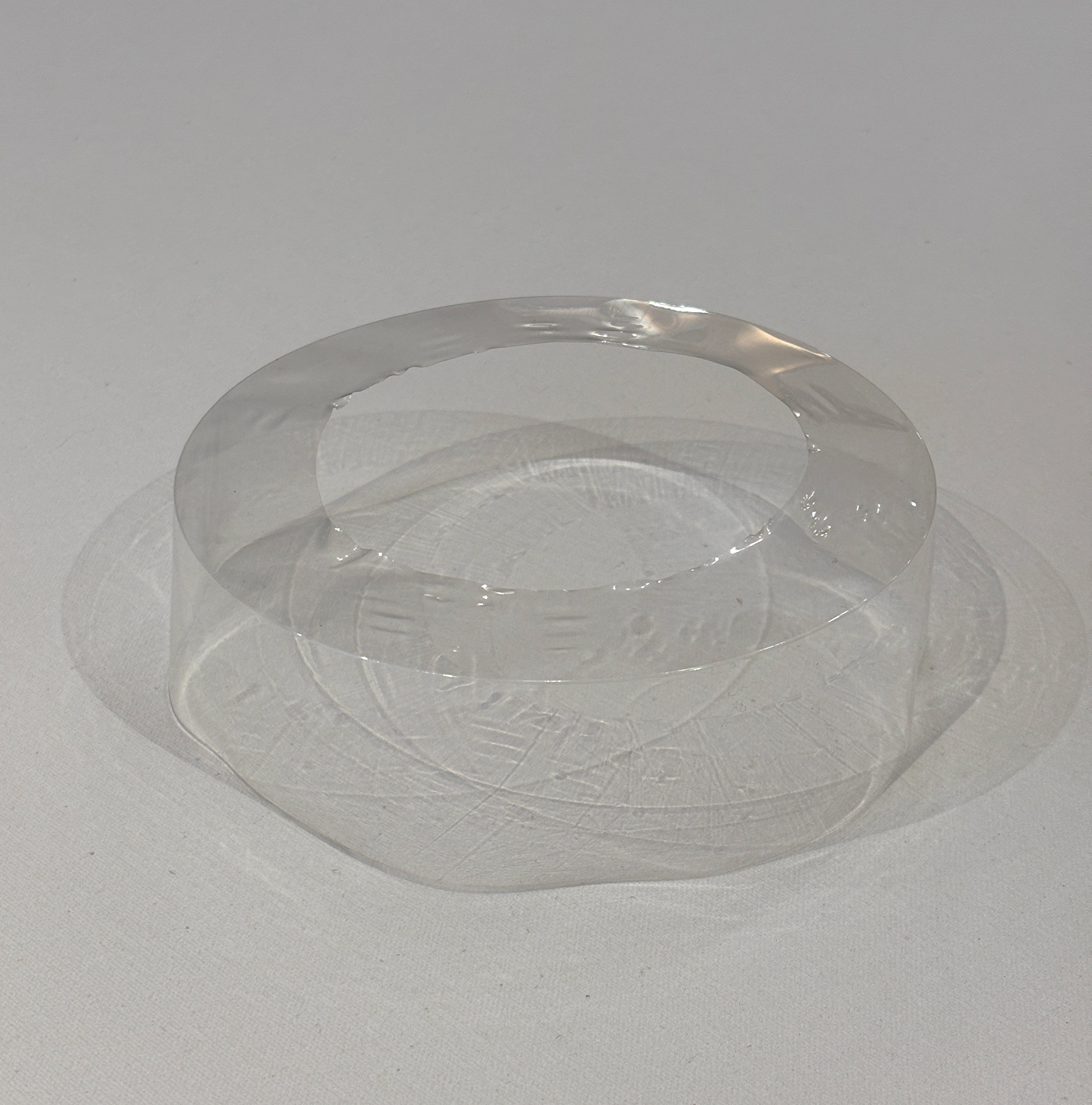 Precinto termocontraíble de PVC virgen, transparente, exhibido sobre fondo neutro. Pieza cilíndrica utilizada para sellado y protección de productos.