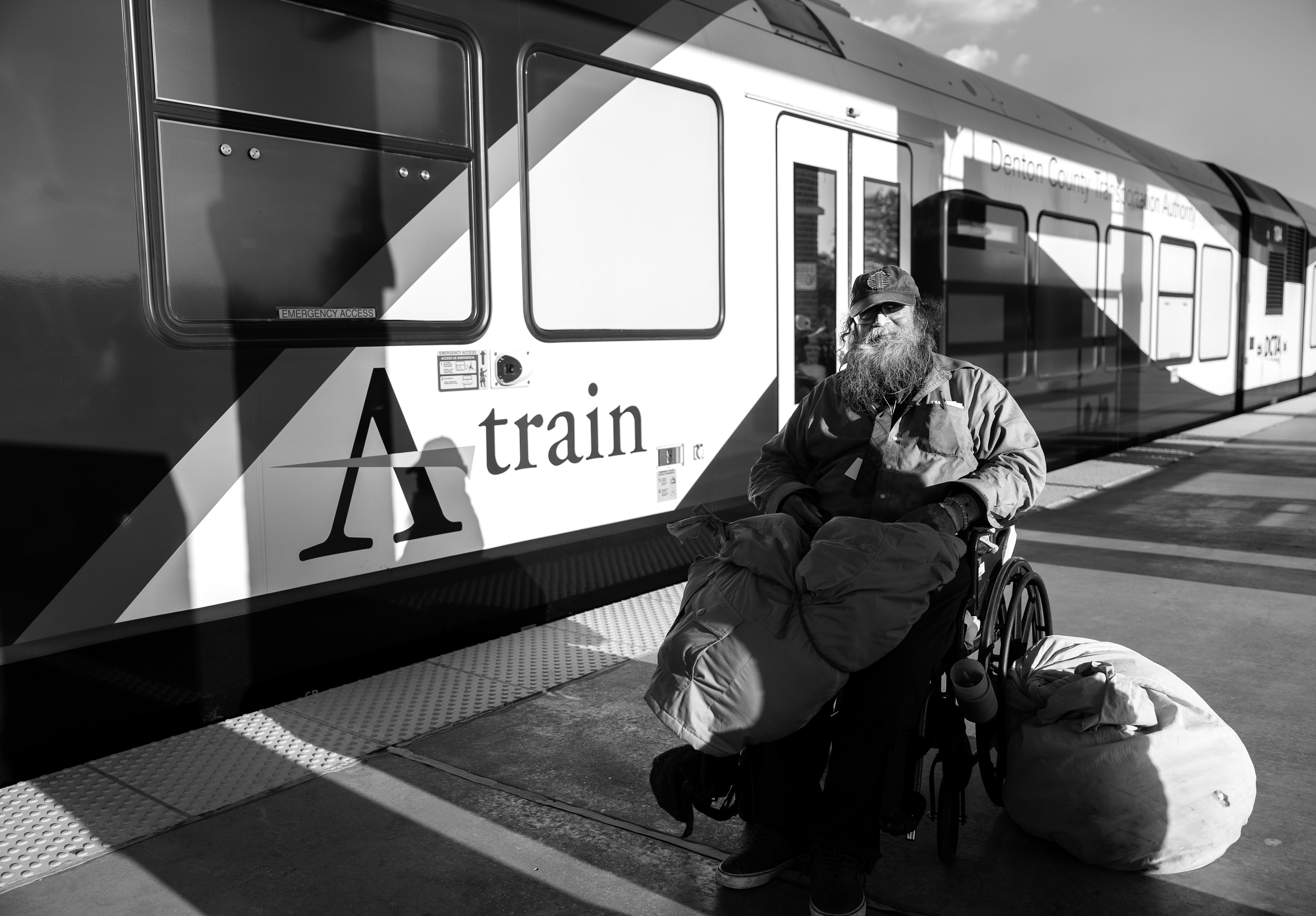 Robert Kennedy sits in his wheelchair in front of a DCTA A-train. Kennedy, who is deaf and nonverbal, communicates by writing on pieces of paper. He carries all his belongings with him and currently lives at a homeless shelter in Denton. The train serves as a regular part of his routine throughout the week.