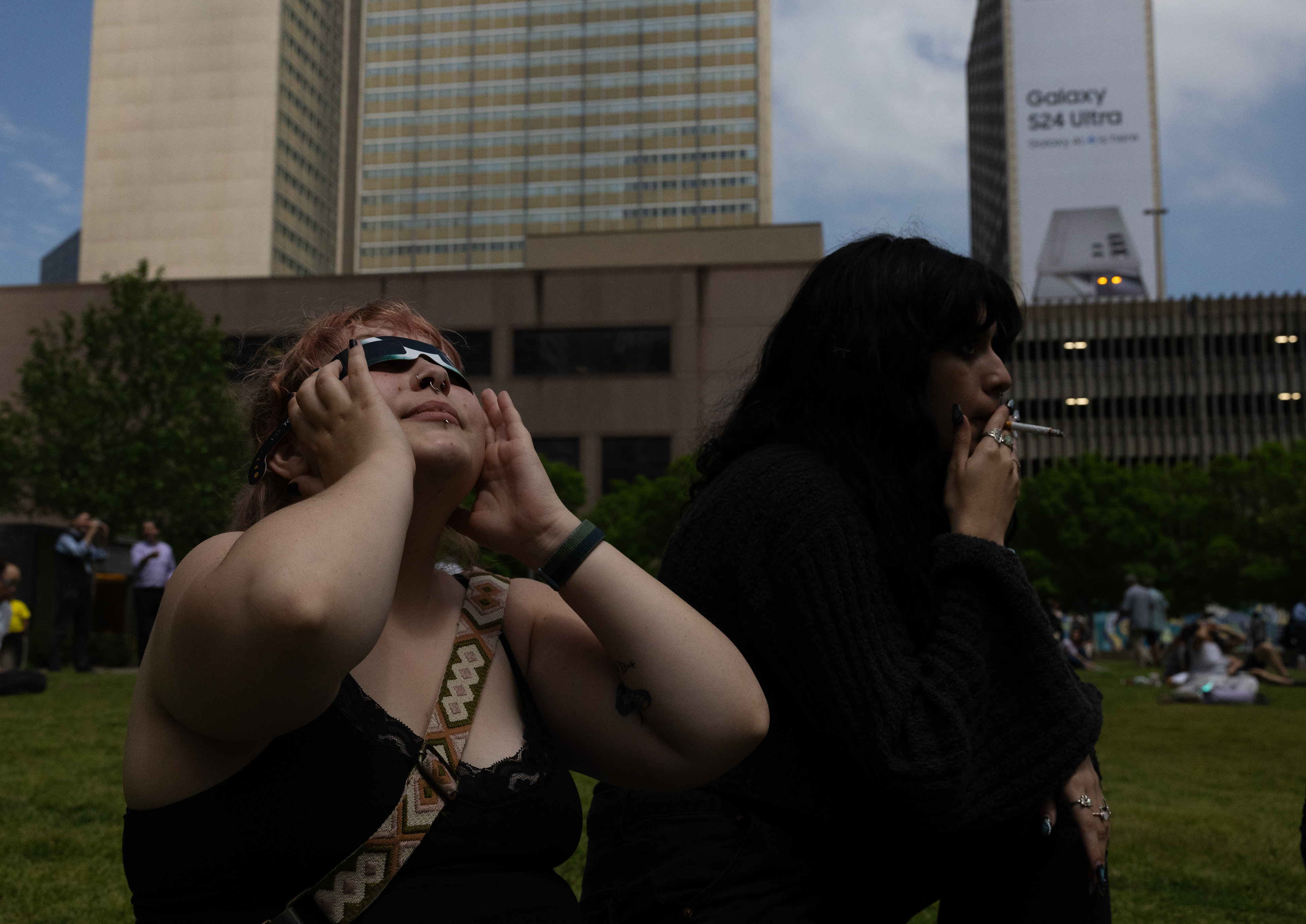 Maddie Richardson watches the ongoing eclipse while sharing a cigarette with their friend Bianca Cuentes. 