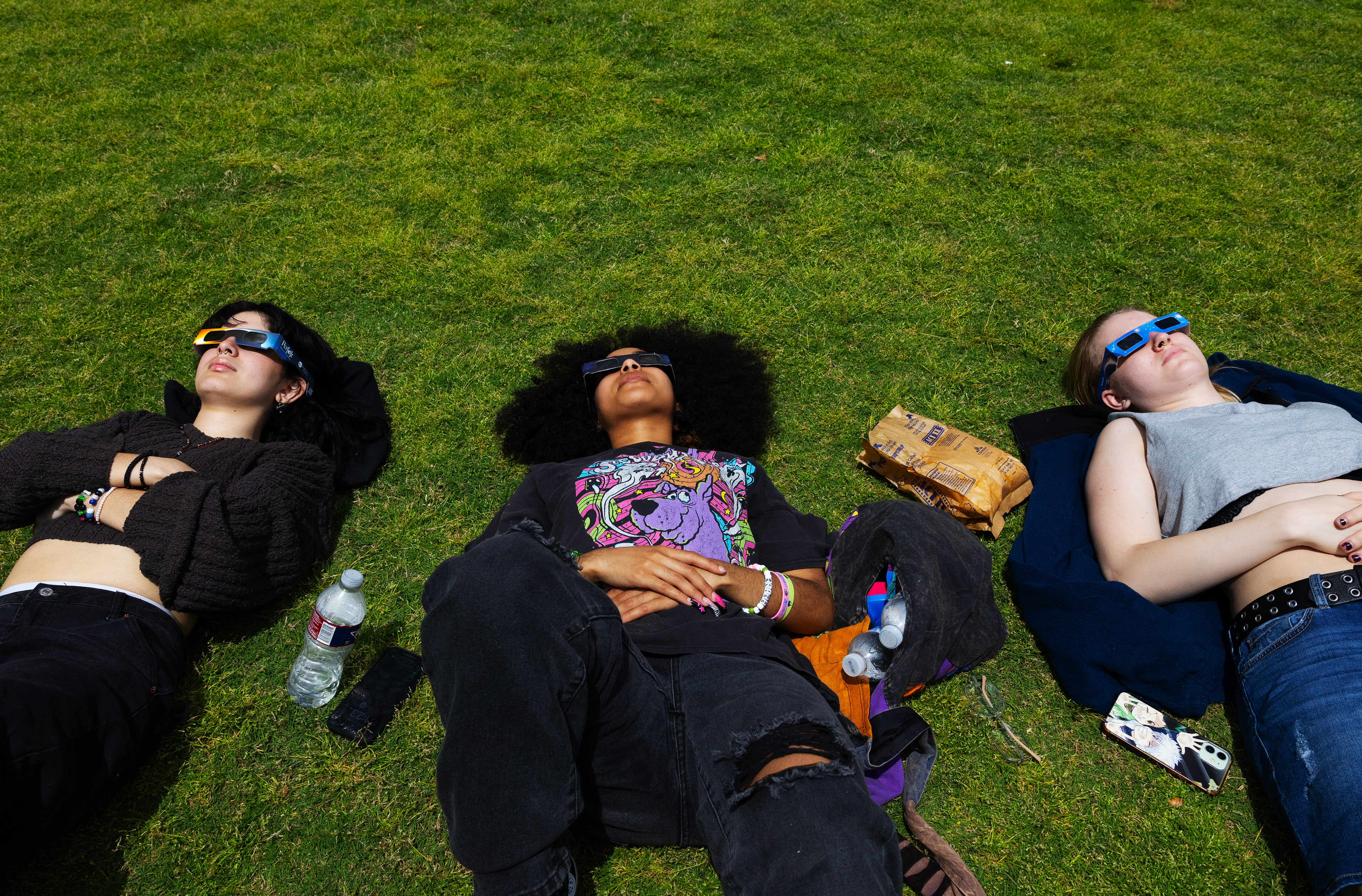 UNT students and friends Bianca, Brie and Kyrin lie together watching the eclipse as it nears totality.