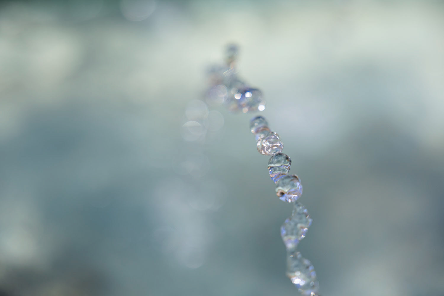Close-up of water droplets midair as they rise from a fountain—capturing a fleeting moment of motion and light through macro photography.
