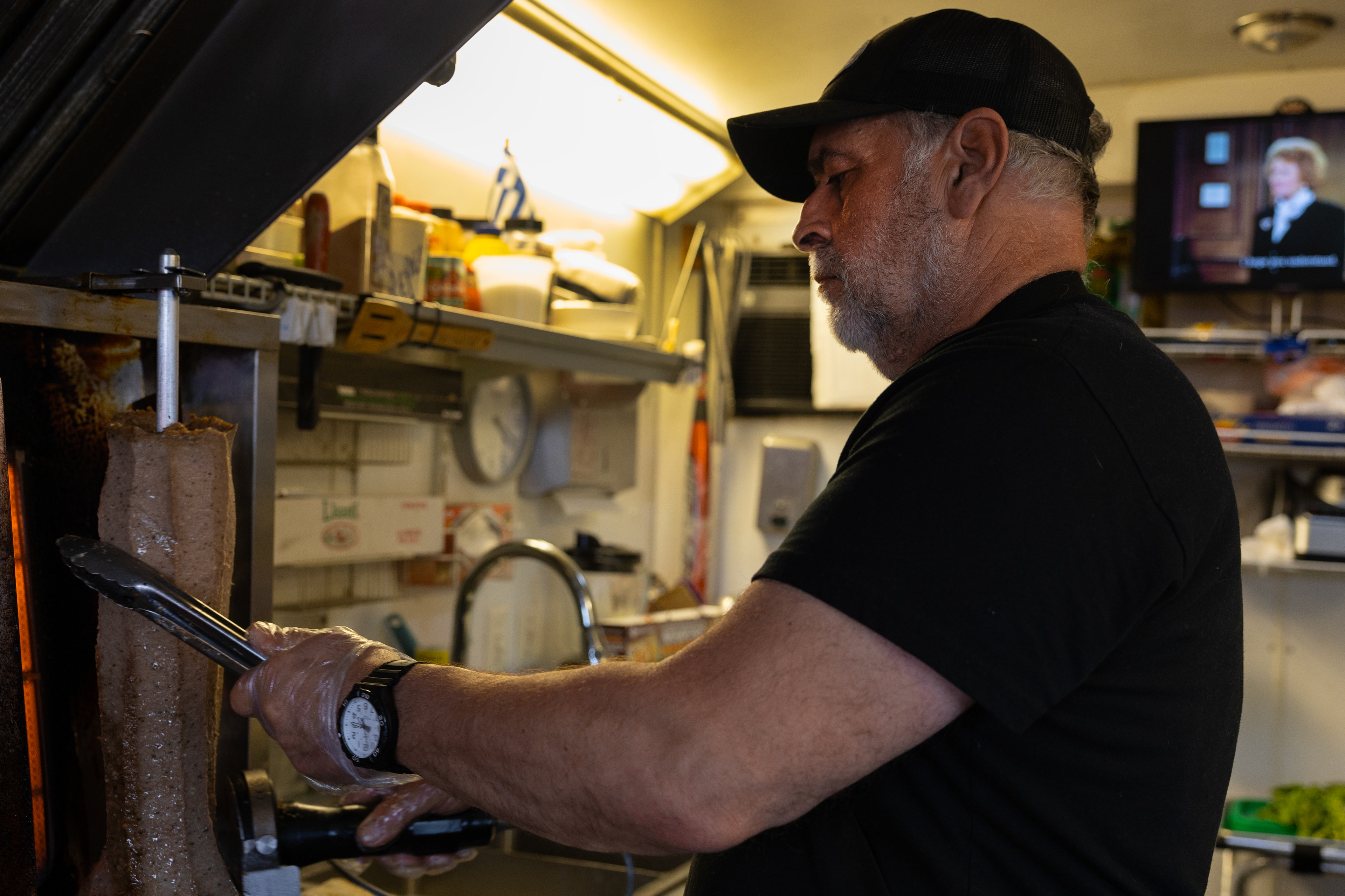 Co-owner of Feta's Lone Star Greek food truck, Lee Zarras, slices off gyro meat for an order he is working on in the truck.