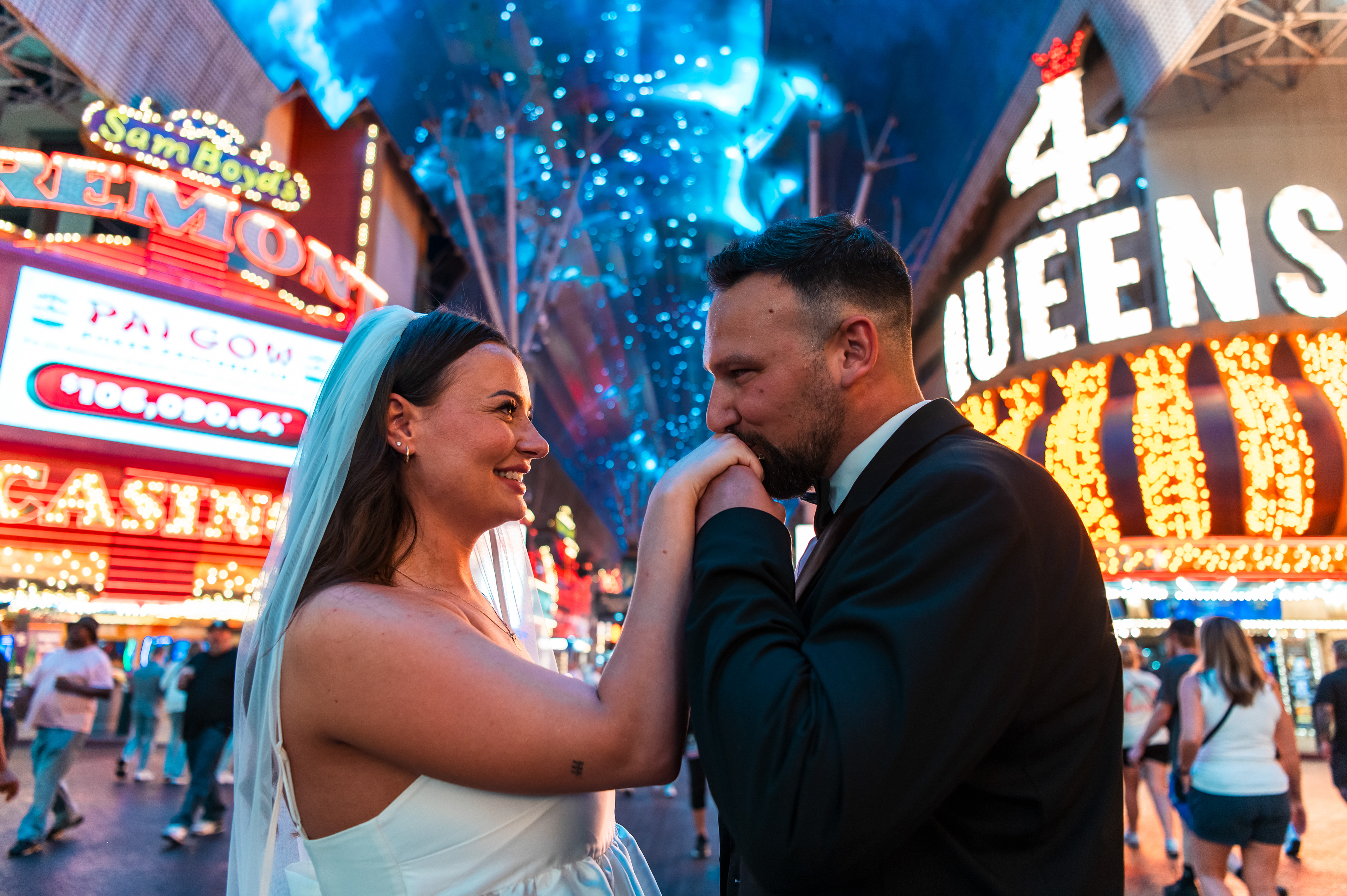 Bride and groom beneath the Fremont Street Experience canopy with the Fremont Hotel & Casino and Four Queens glowing in the background.