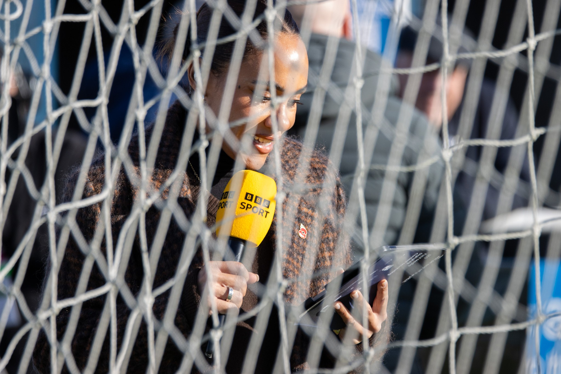 BBC Presenter Alex Scott reads on her phone.