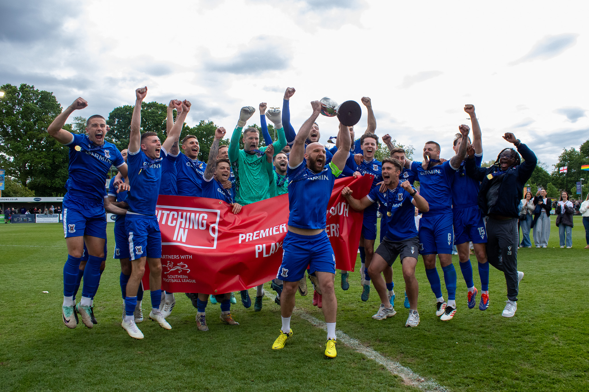 Mike Carter lifts the Southern League Premier Division South Promotion Play-Off trophy as the team celebrates around him.