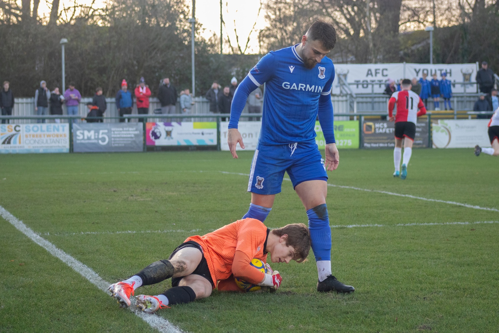 Tony Lee stands over Pat Nash as he clutches the ball.