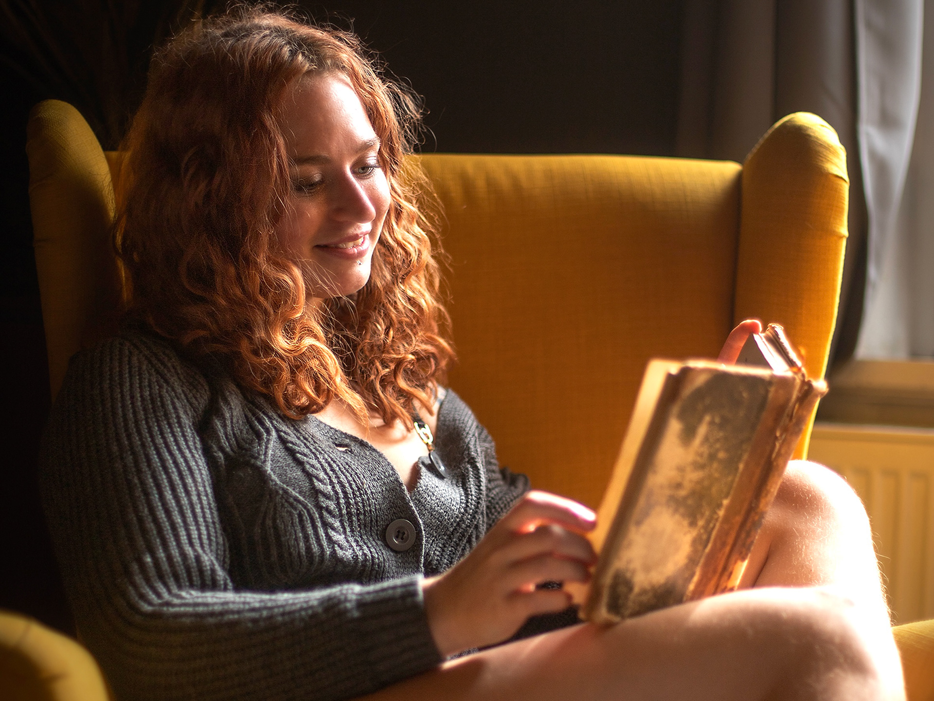 Frau im Sessel ließt ein Buch Nahes Portrait mit ruhigem Blick und weichem Licht, Portraitfotografie in Bremen
