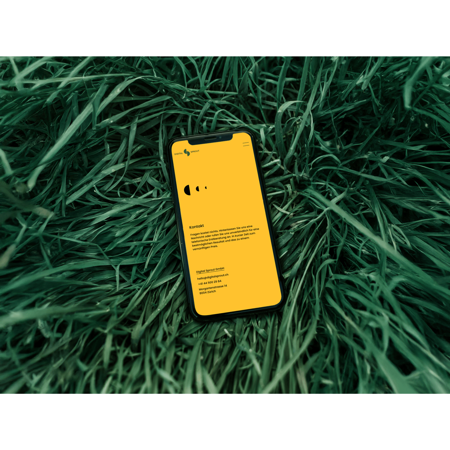 A phone on the grass showing a website for a digital agency