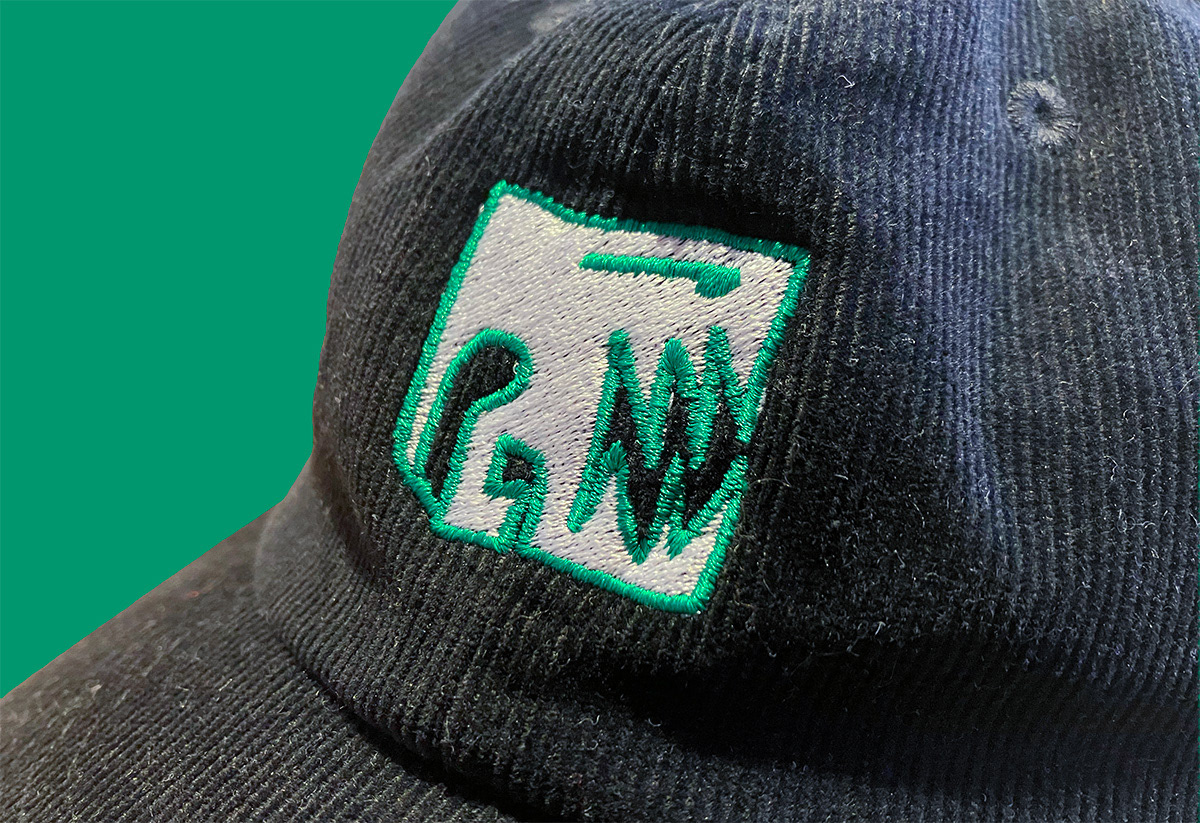 Schwarze Cord-Cap mit einem grün-weiß gestickten Manifesto-Motiv