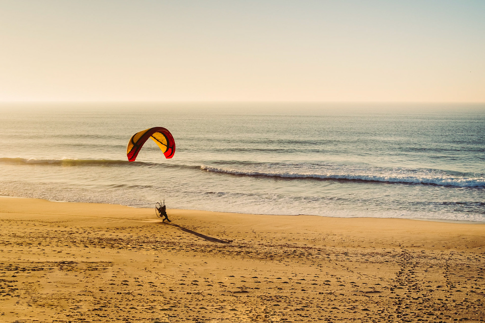 Powered paraglind hobbist practicing on a beach during a sunset