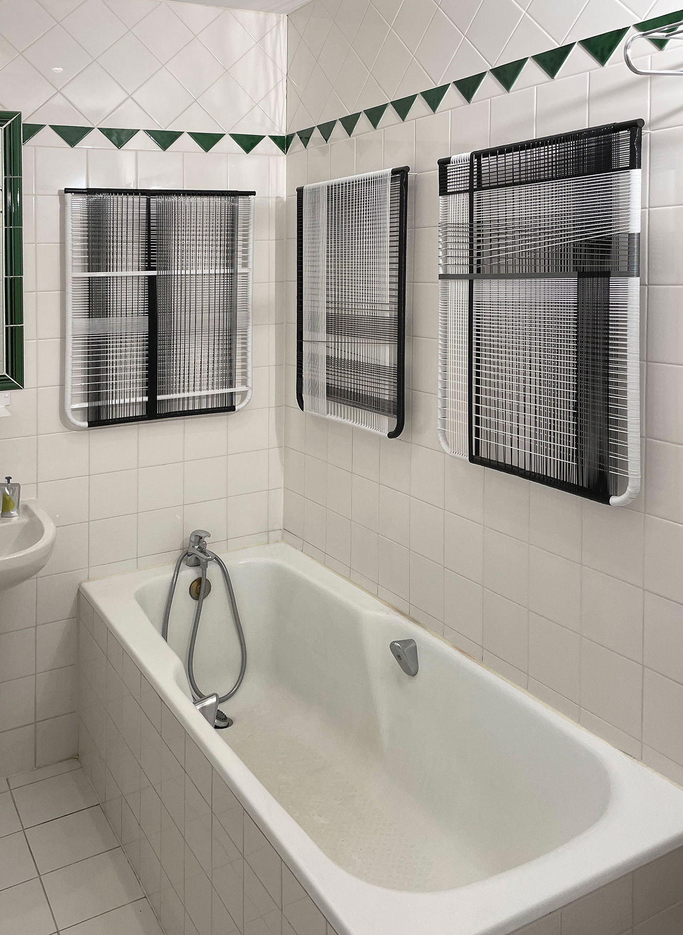 3 oeuvres réalisées en fil PVC sur châssis métal sont accrochées dans la salle de bain.