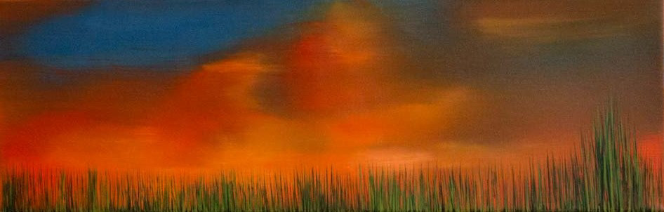 sundown with vibrant yellow and red tones reflected on the clouds with visible grass at the bottom of the image