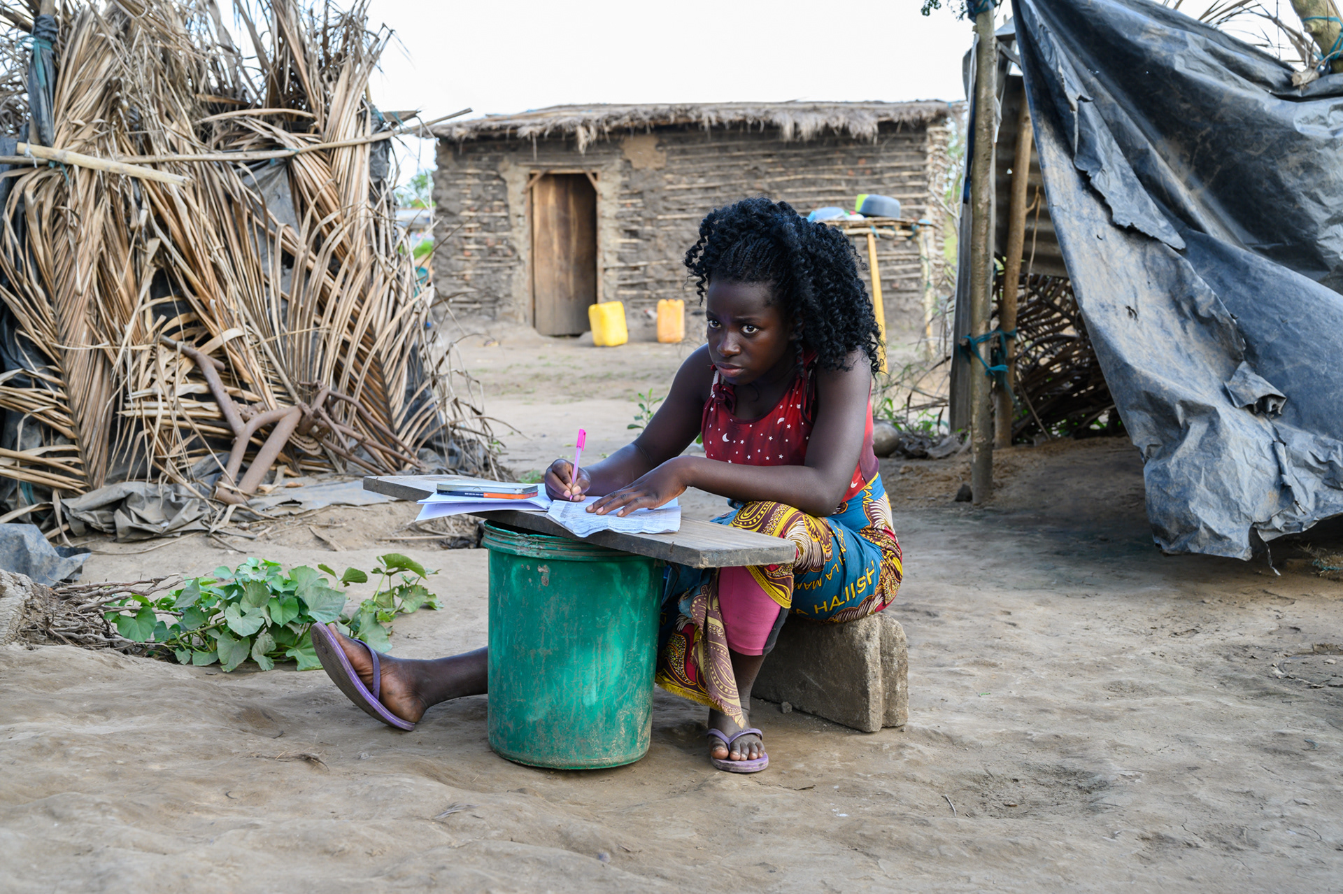 Helena Limao Fernando, age 16, studies outside her temporary home in the Josina Michelle neighborhood of Nhamatanda devastated by Cyclone Idai. Her older sister was killed in a building collapse during the storm. Helena is in 10th grade and cares for herself and younger siblings in this home on her mother's property.