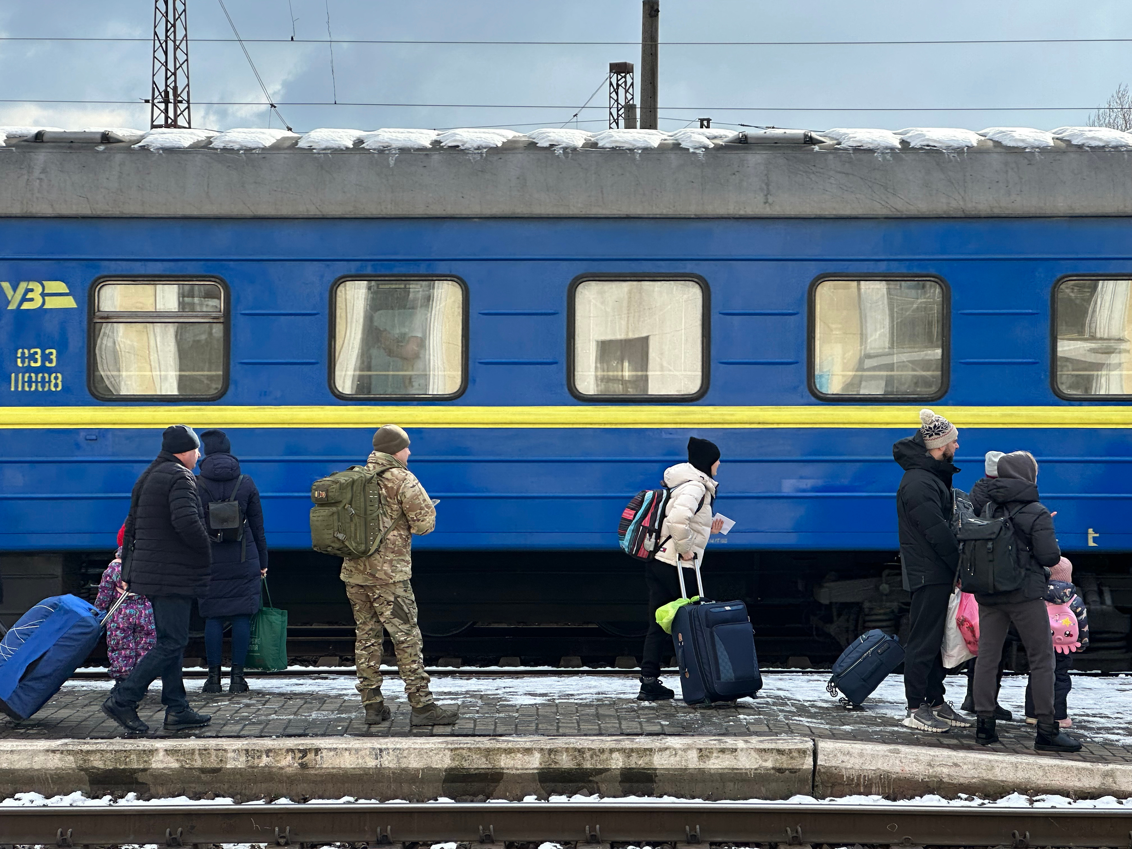 A Ukrainian soldier waits to board the train from Mukachevo, Ukraine, to Lviv and locations further east toward the fighting after saying goodbye to his family on the platform.