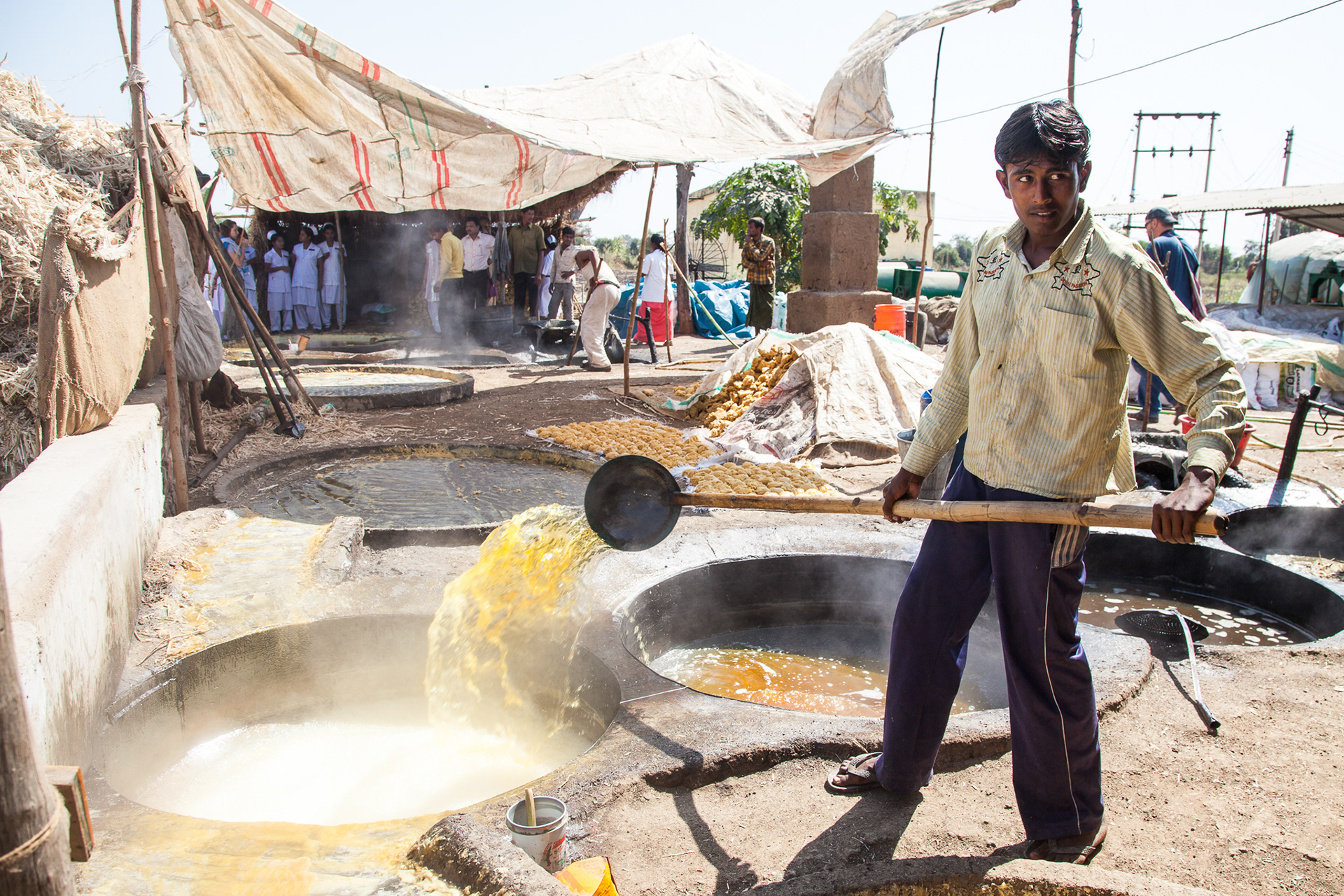 A worker at a jaggery (cubed cane sugar) plant moves boiling cane juice between vats.