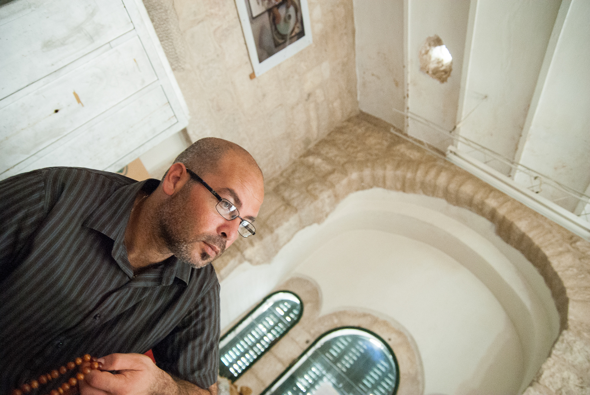 An educator sits under a hole caused by a mortar shell in this Bethlehem school.