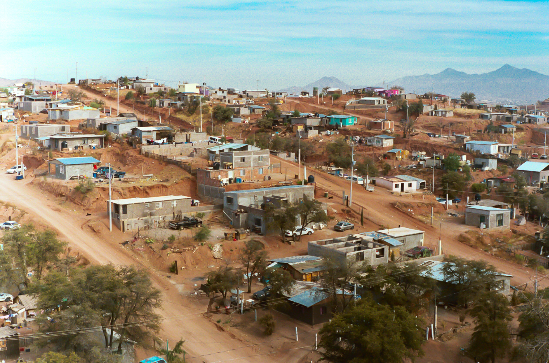 Hillside "invasion community" near foreign owned factories in Nogales, Mexico. These communities are called "invasion communities" because landowners offer them up in a land grab for the sole purpose of allowing people to build rudimentary living quarters without charging for the land. Once the shacks and houses have been established "service fees" are established by the landowner based on the amount of land and the quality of the house. This particular "invasion community" has no running water or sewer service. A water truck provides potable water two or three times a week for sale.