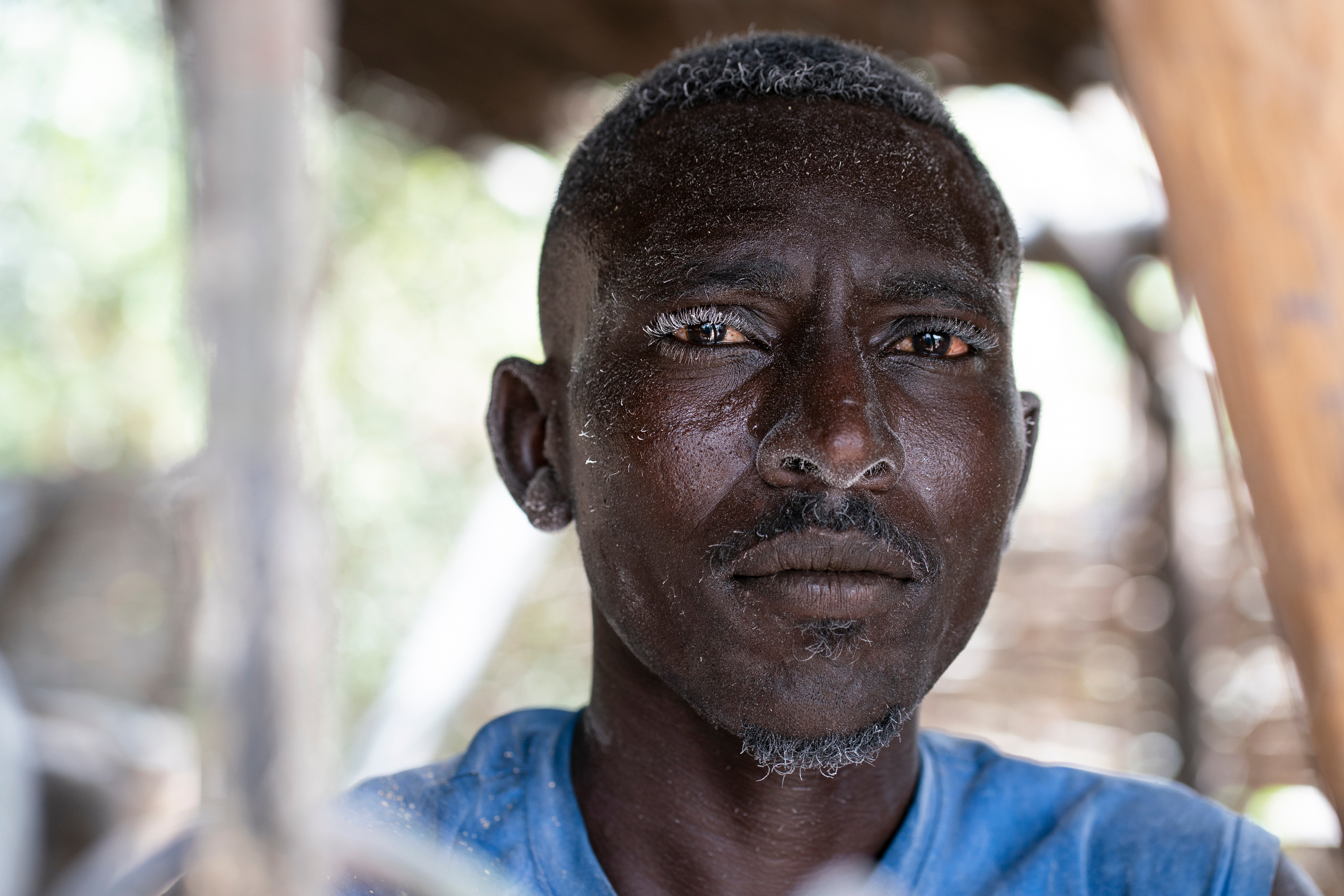 Mohammad Abdullah Issa operates a grain mill in the Beliel camp for internally displaced persons in South Darfur, Sudan. The fine dust of millet flour coats his hair and body after a day's work.