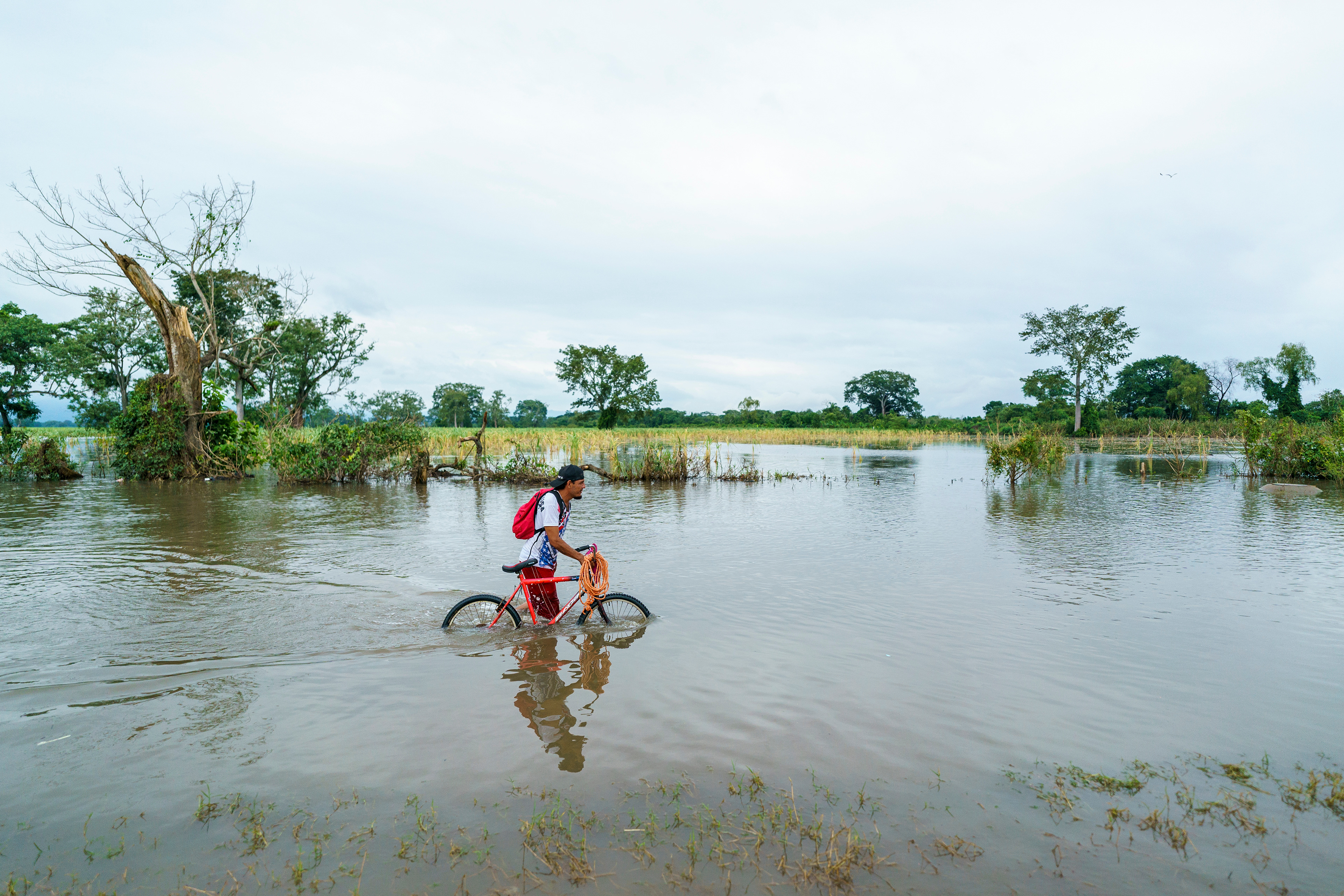 A man walks his bicycle along a flooded road outside Choloma, Honduras, following Hurricane Iota in November 2020.