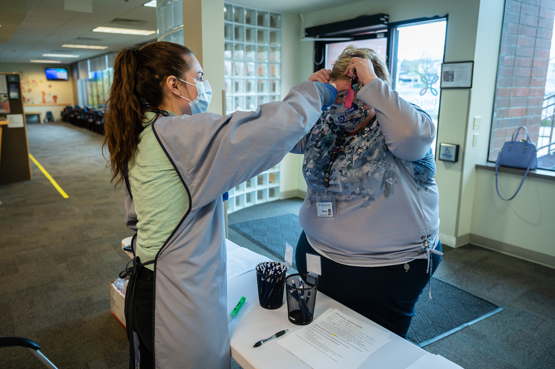 A staff member at Unity Care NW in Bellingham, Washington has her temperature checked and signs off on her lack of COVID-19 symptoms prior to beginning her shift at the clinic.