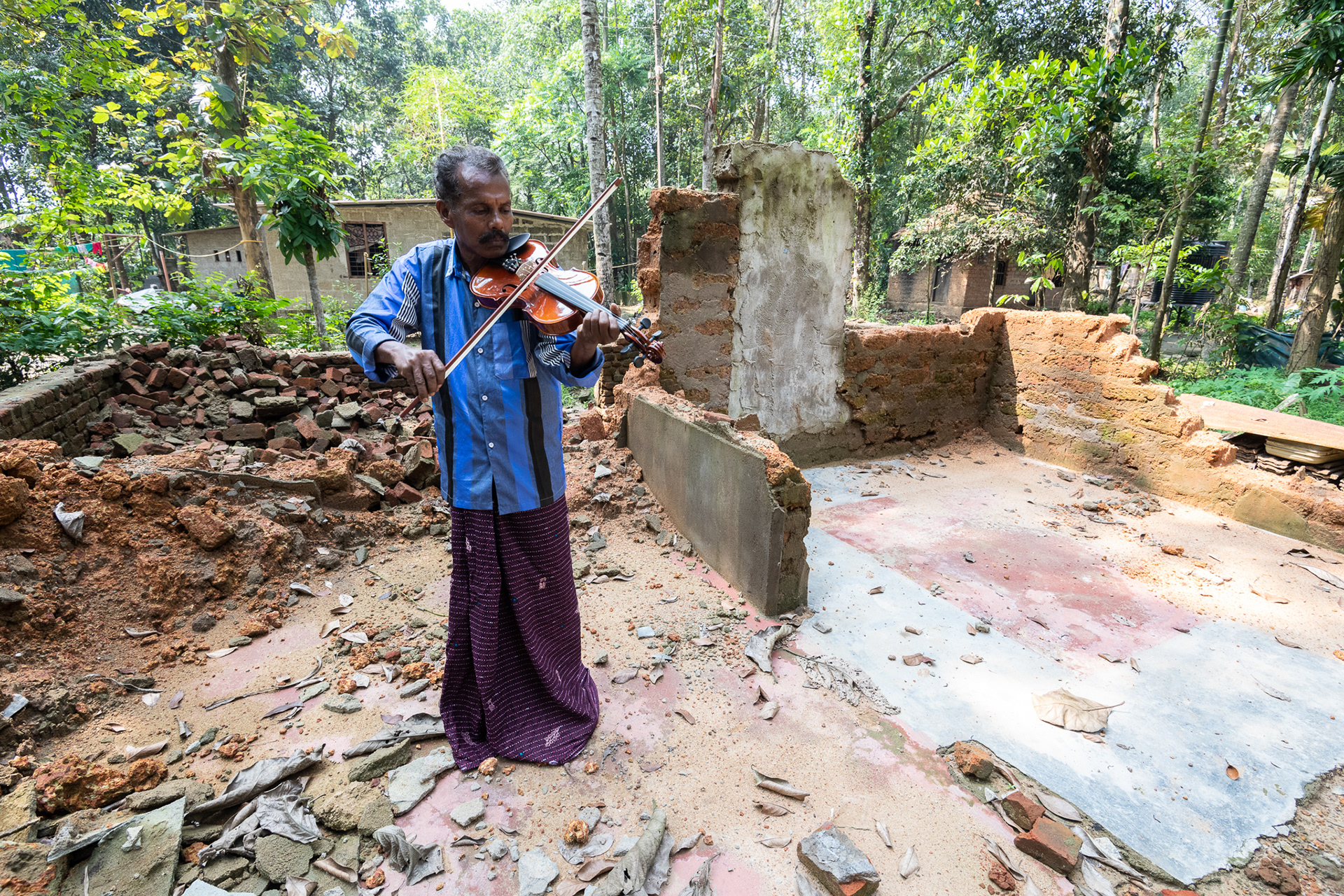 Joseph P. S., a music teacher in Kurichimuttom, the largest Dalit colony in Kerala, India, plays the violin the in ruins of his home destroyed by August 14-18, 2018 flooding. All his instruments swept away in the flood, this violin was a gift from an NGO. The community was submerged in 3-5 meters (10-15 feet) of water.