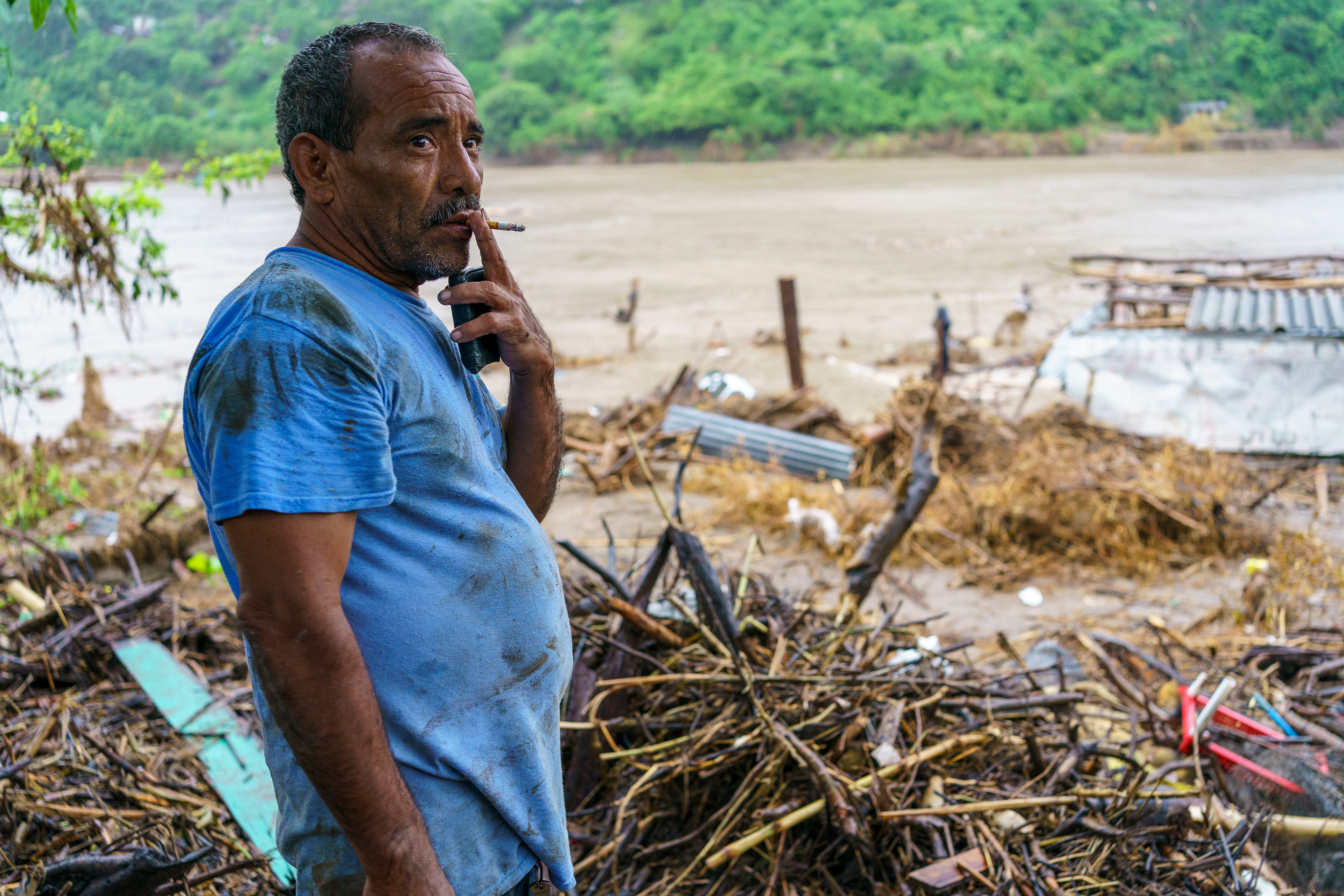 Rene Artuo Lopez Roques drags on a cigarette as he overlooks the ruins of his third home lost to the waters of the Chamelecón River in 30 years. “We stay here because we’re poor,” he said, standing in the mud deposited by Hurricane Eta in early November 2020. “We cannot afford to go anywhere else.”