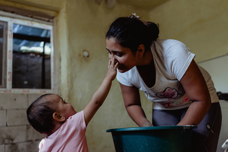 Mihaela, 26, and her daughter in their kitchen, making pancakes. Gaujani commune, Giurgiu county.