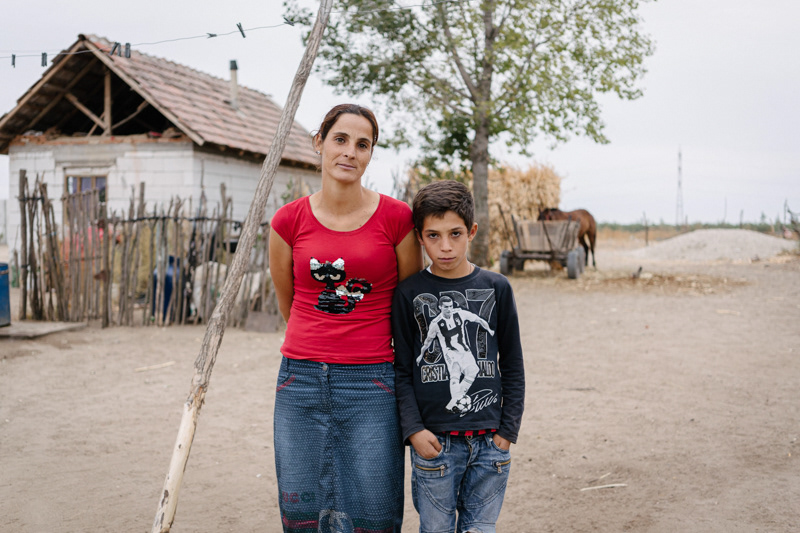 Liliana Raluca, 28, with her son. Behind them, beyond the bounds of their household, lies a vast and unpopulated territory that makes every attempt to go out at night dangerous, because of the stray dogs roaming nearby. Ocolna village, Dolj county