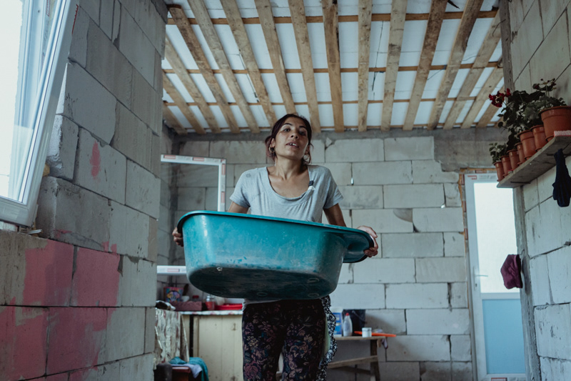 Irina, preparing the bucket for the children's bath time. Pietrisu village, Giurgiu county.