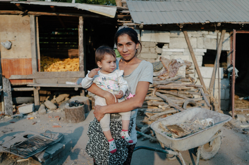 Irina, 25, with her youngest son. She came back from working in Spain, and is now waiting for her husband, who is still there, to return home, so they can continue building their house. Pietrisu village, Giurgiu county