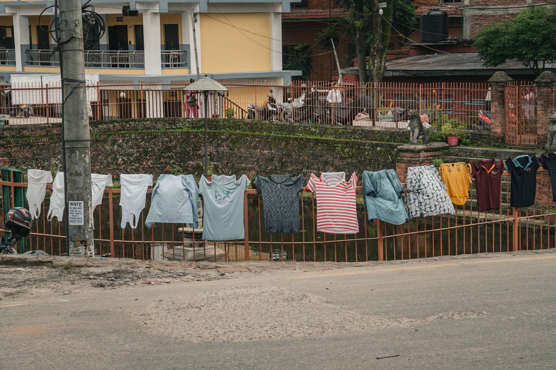 In Nepal, there are no dryers or much affordable electricity (limited to toilets and lights) for the most part. Clothes are hung on fences, in this one, hung on the edge of a fountain.