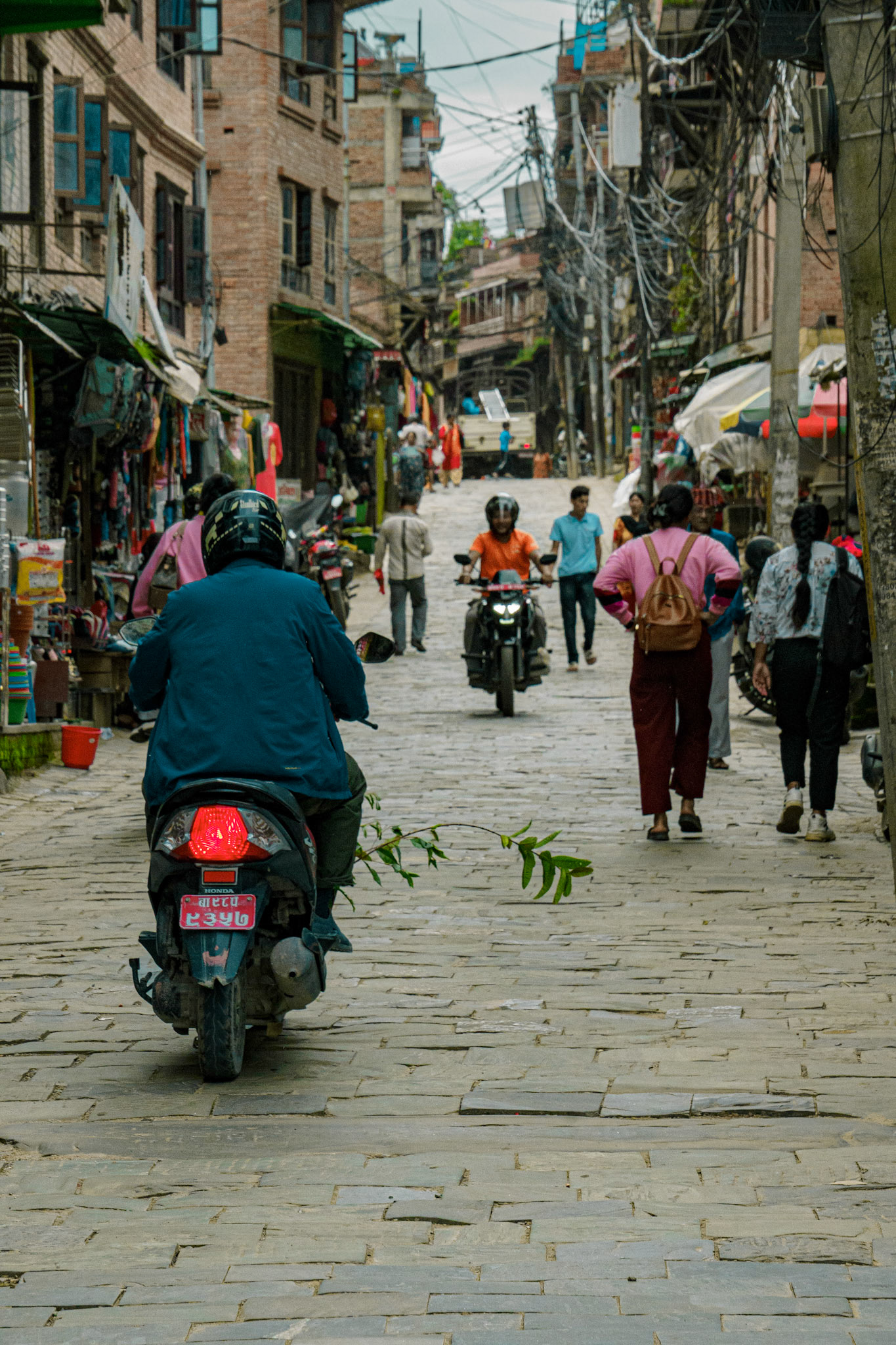 Citylife in Nepal contrasts with modern society. No yellow lines, people share the street together. Mopeds are a commonality.