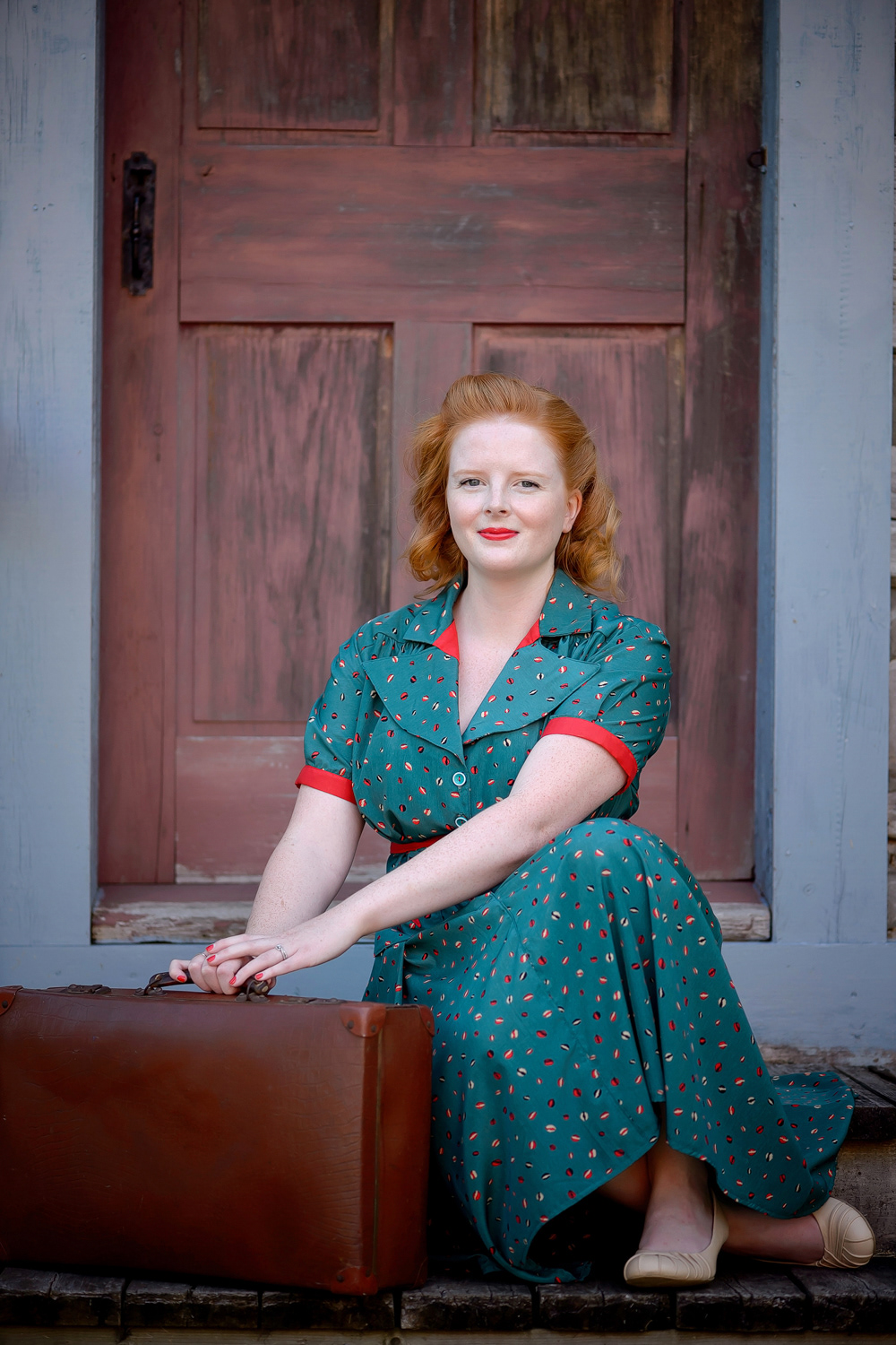 1940s Day Dress: This rayon dress inspired by the 1940s is gathered along the shoulders, front and back. with darts to create a fitted waist. The dress is made with matching red detailing and a custom belt.