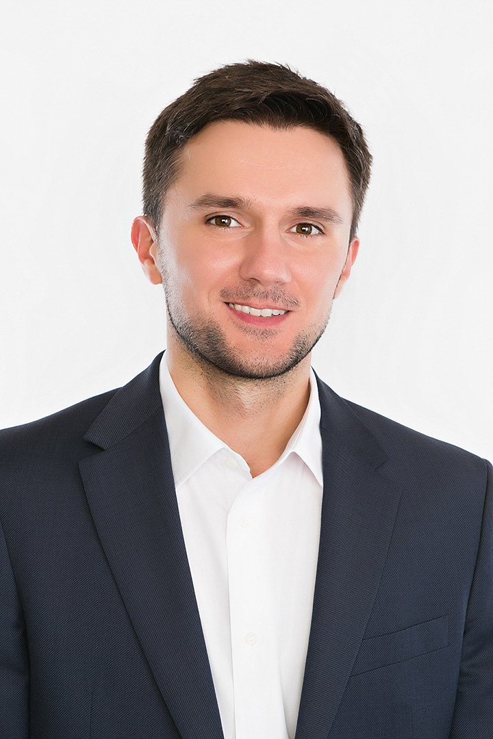 Corporate headshot of a male executive photographed against a white background.