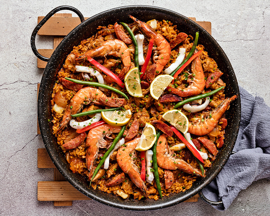 A food photograph of a paella dish. The image is used as an introduction to an article of Elevating Dining Through Visuals which was written by Adobe..