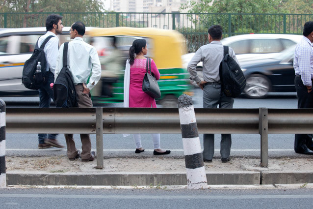 A la sortie du travail, femme attend une voiture au bord d'une route passante.