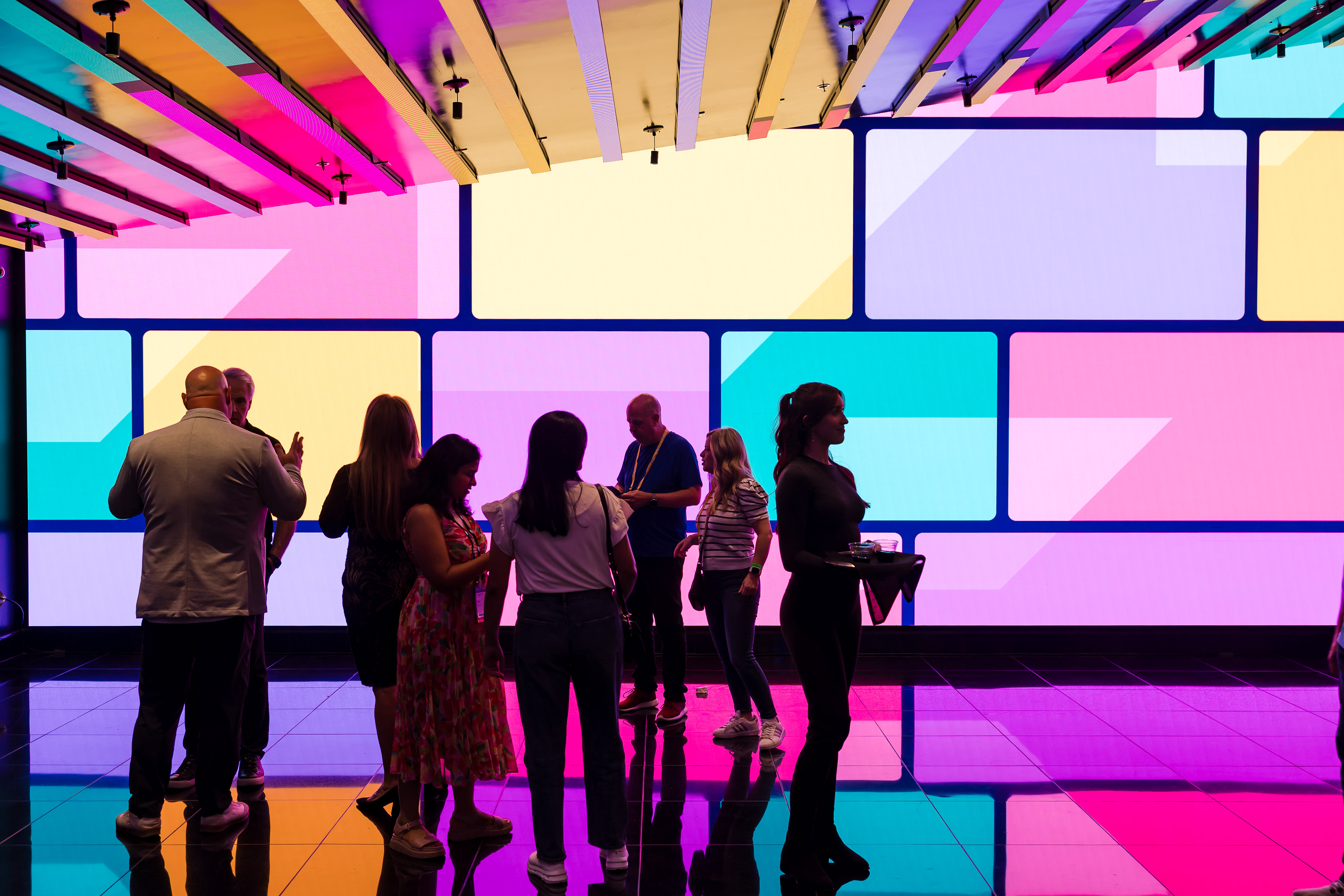 Colorful geometric LED ceiling installation with attendees mingling