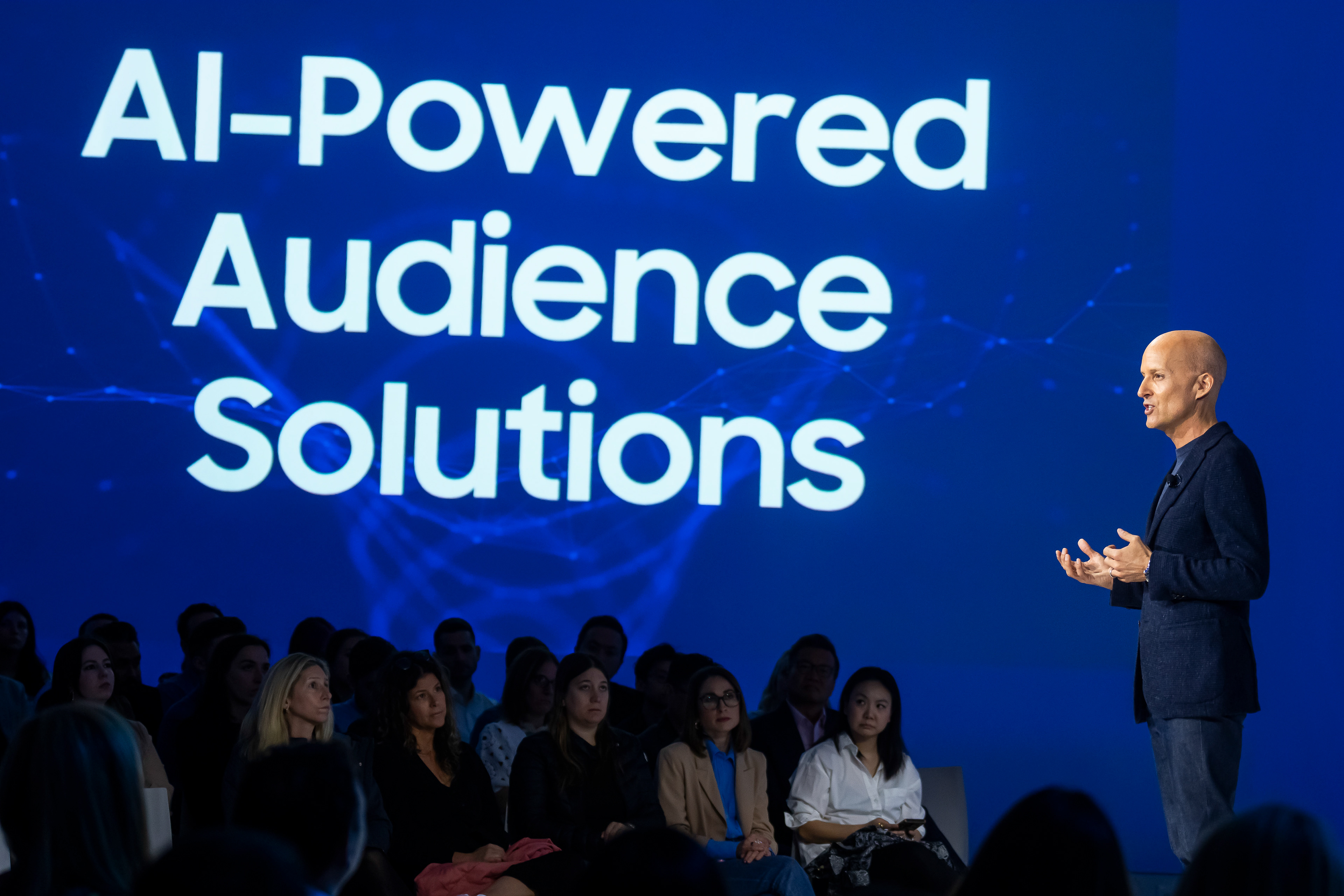 AI-Powered Audience Solutions presentation slide with speaker on stage