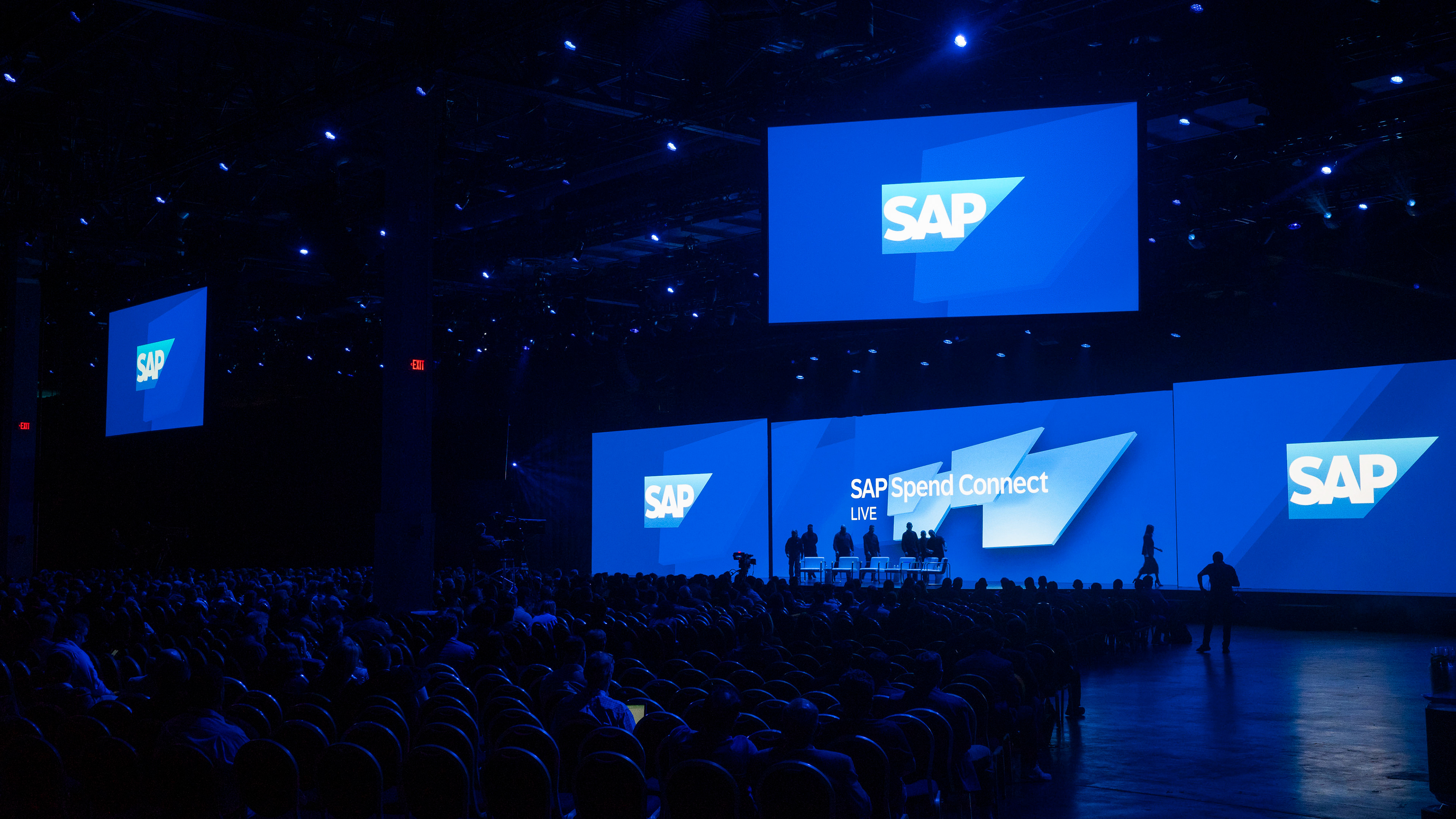 Wide keynote stage shot with five feature-tile screens