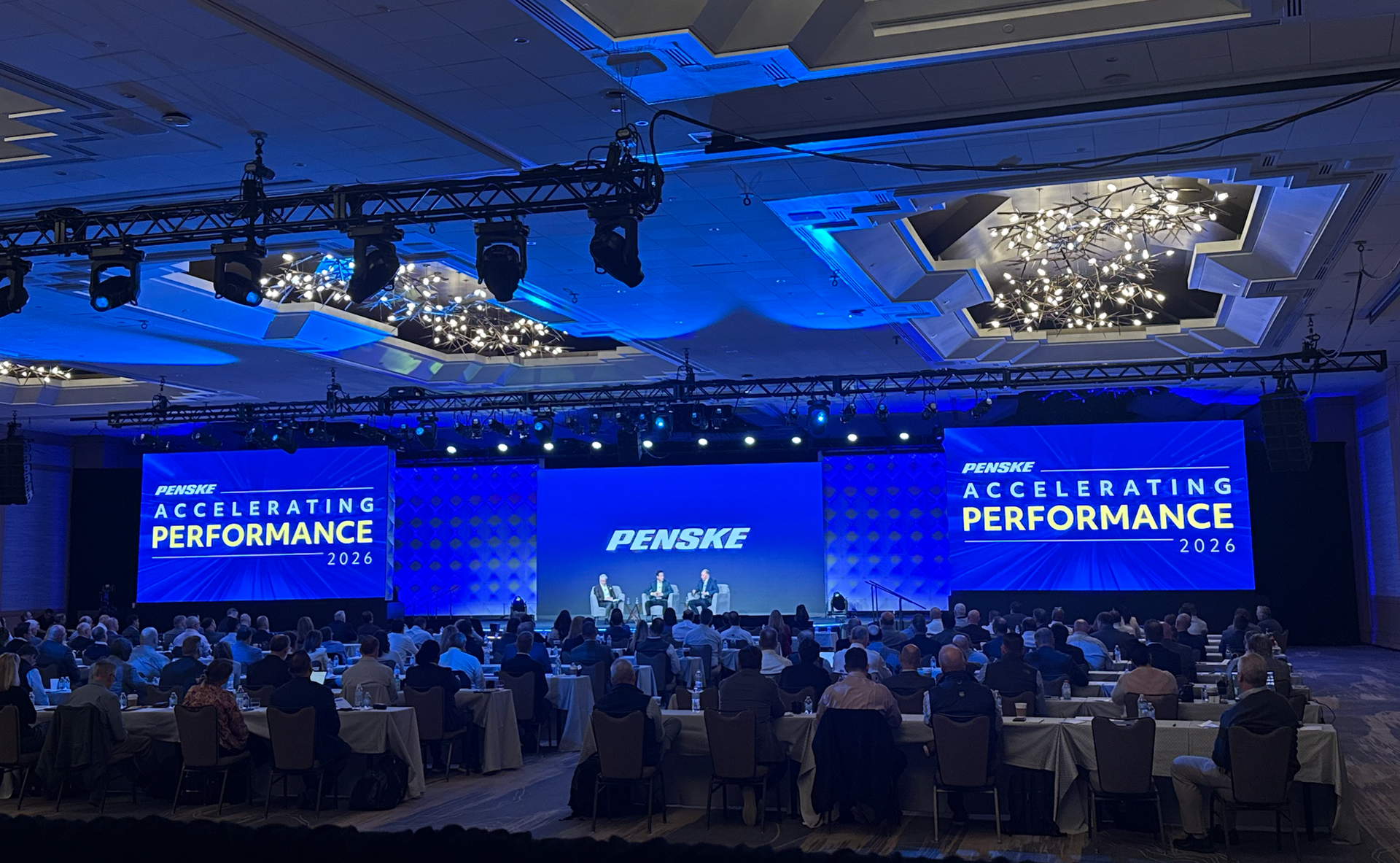 Wide shot of a full ballroom facing dual Accelerating Performance screens