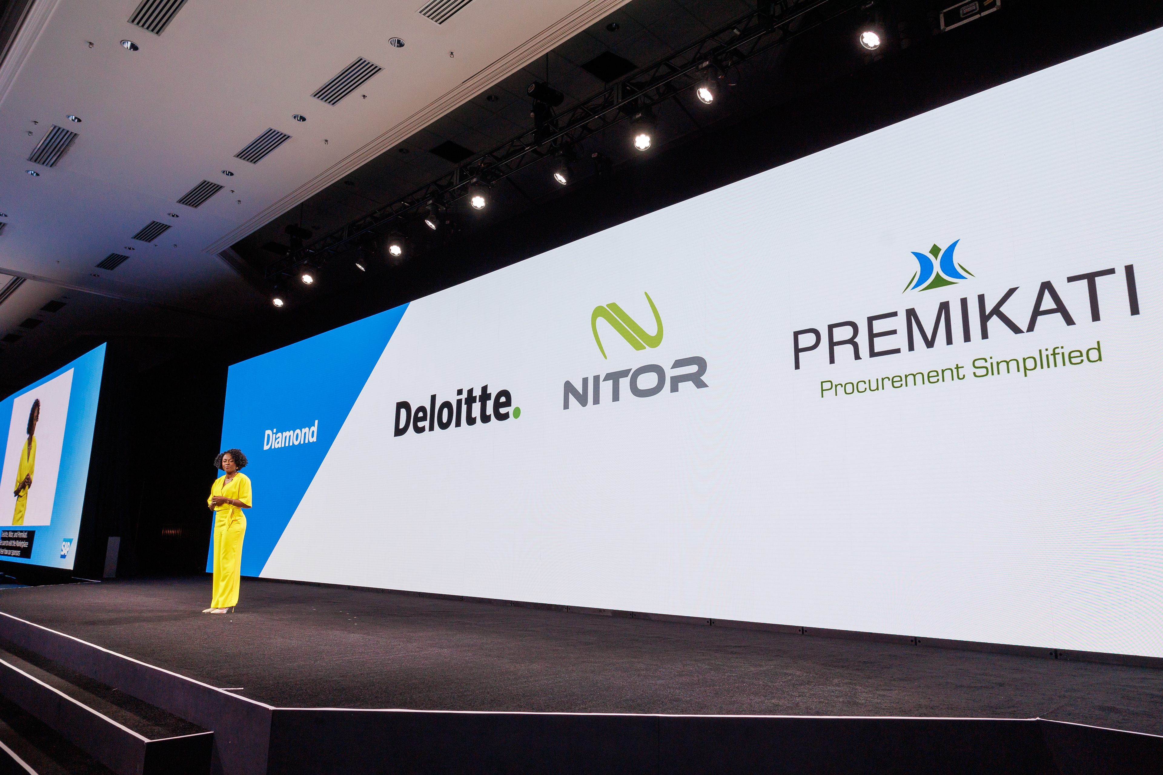 Wide stage shot with brand-values panel words over the audience