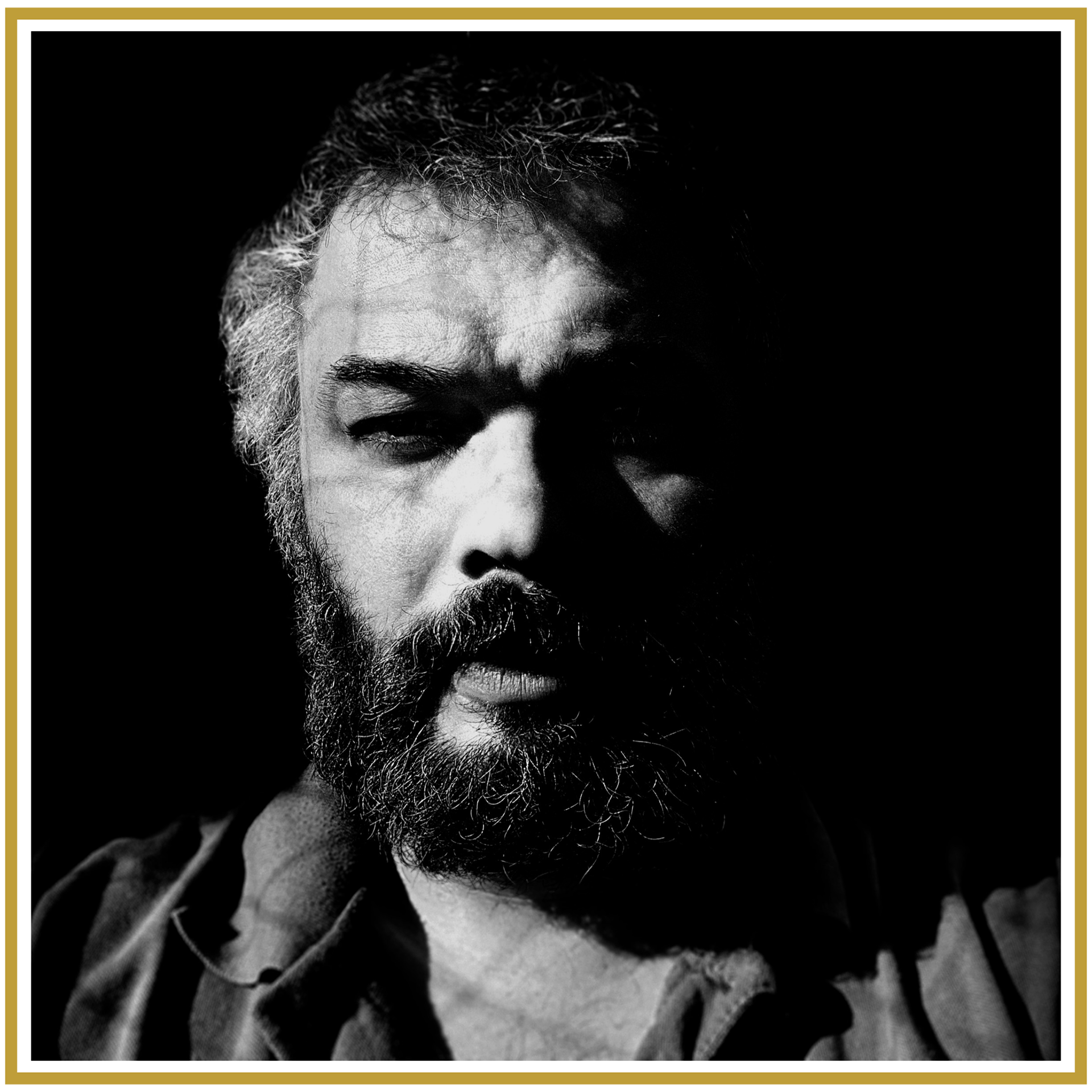 A black and white photo of Neil Alan Bell with a heavy thick beard wearing a cotton shirt with a soft collar in a gold boarder frame