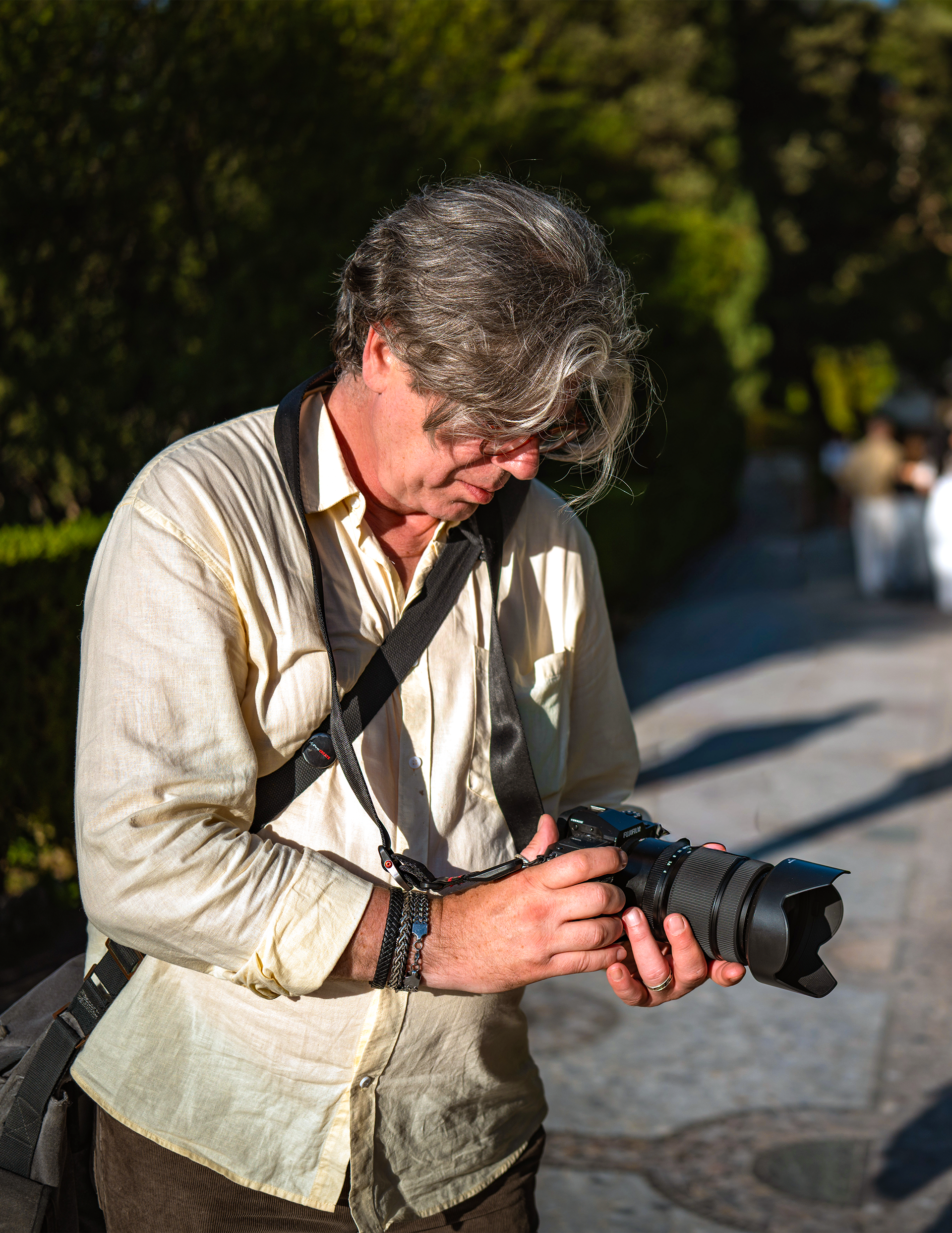 Viktor Turbá, deep in focus, checks his camera settings along a sunlit path at Villa d’Este, surrounded by fountains and greenery.