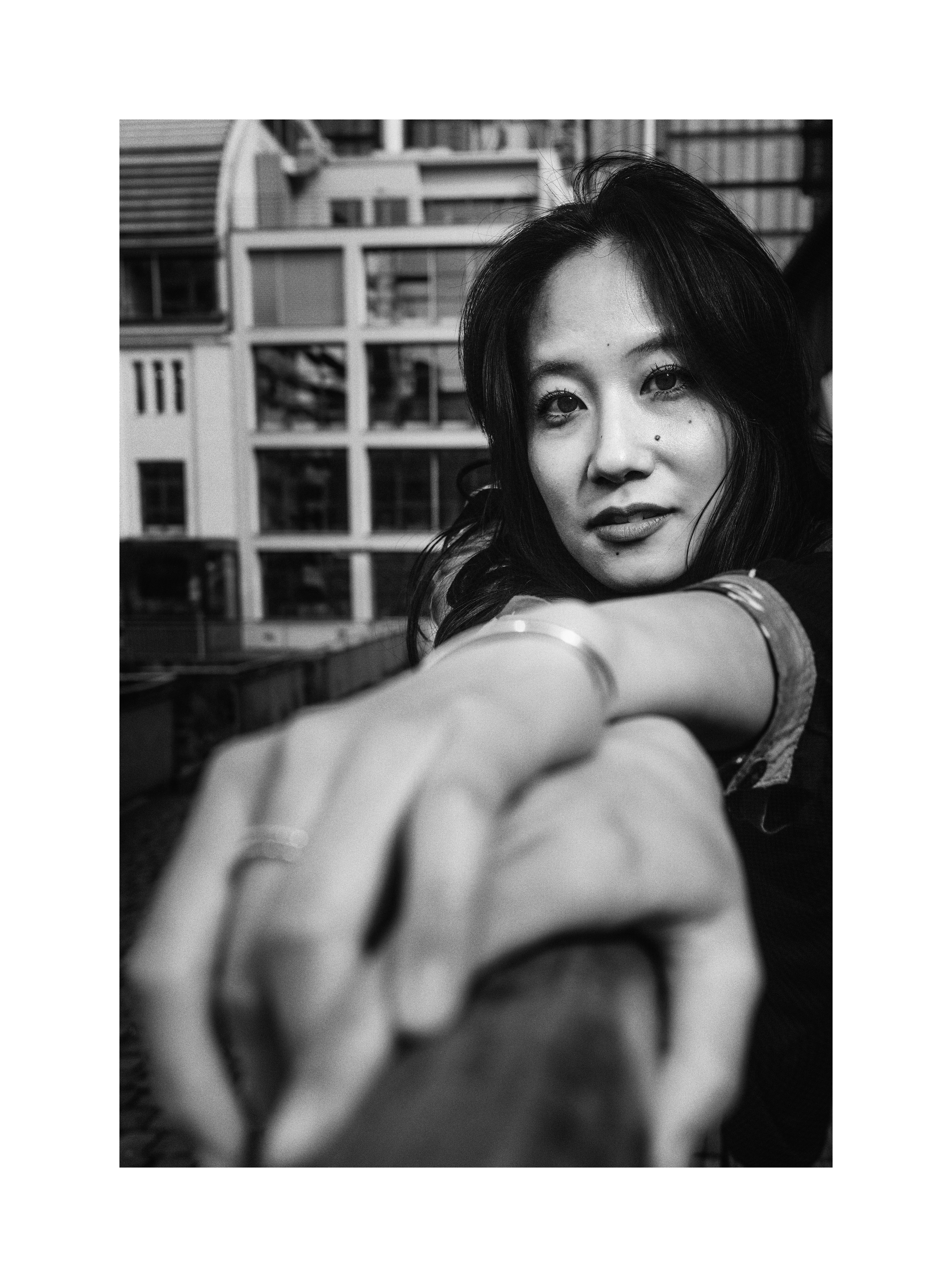 Black and white street portrait of Madoka reaching toward the camera
