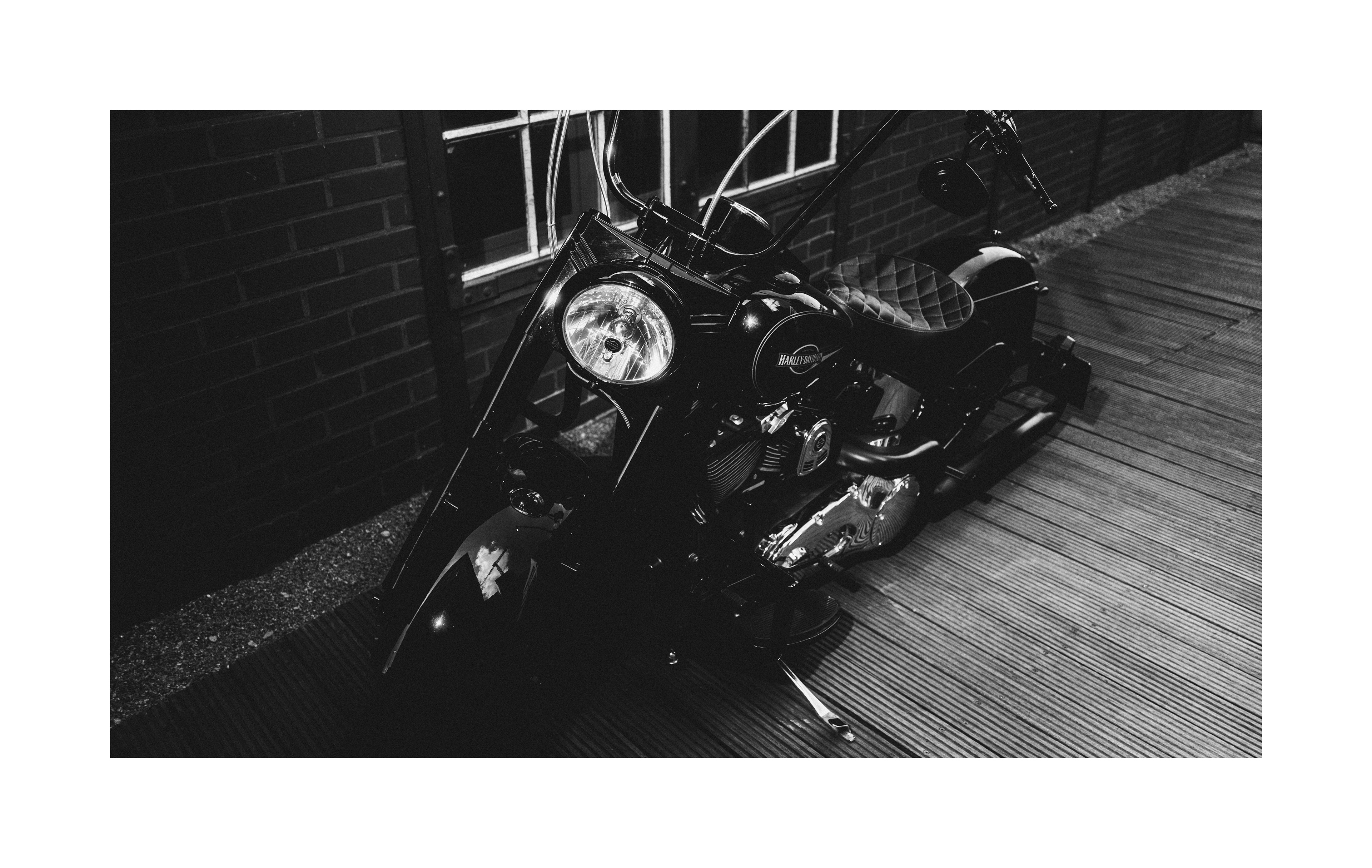 Black and white photograph of a Harley-Davidson motorcycle in an industrial setting.
