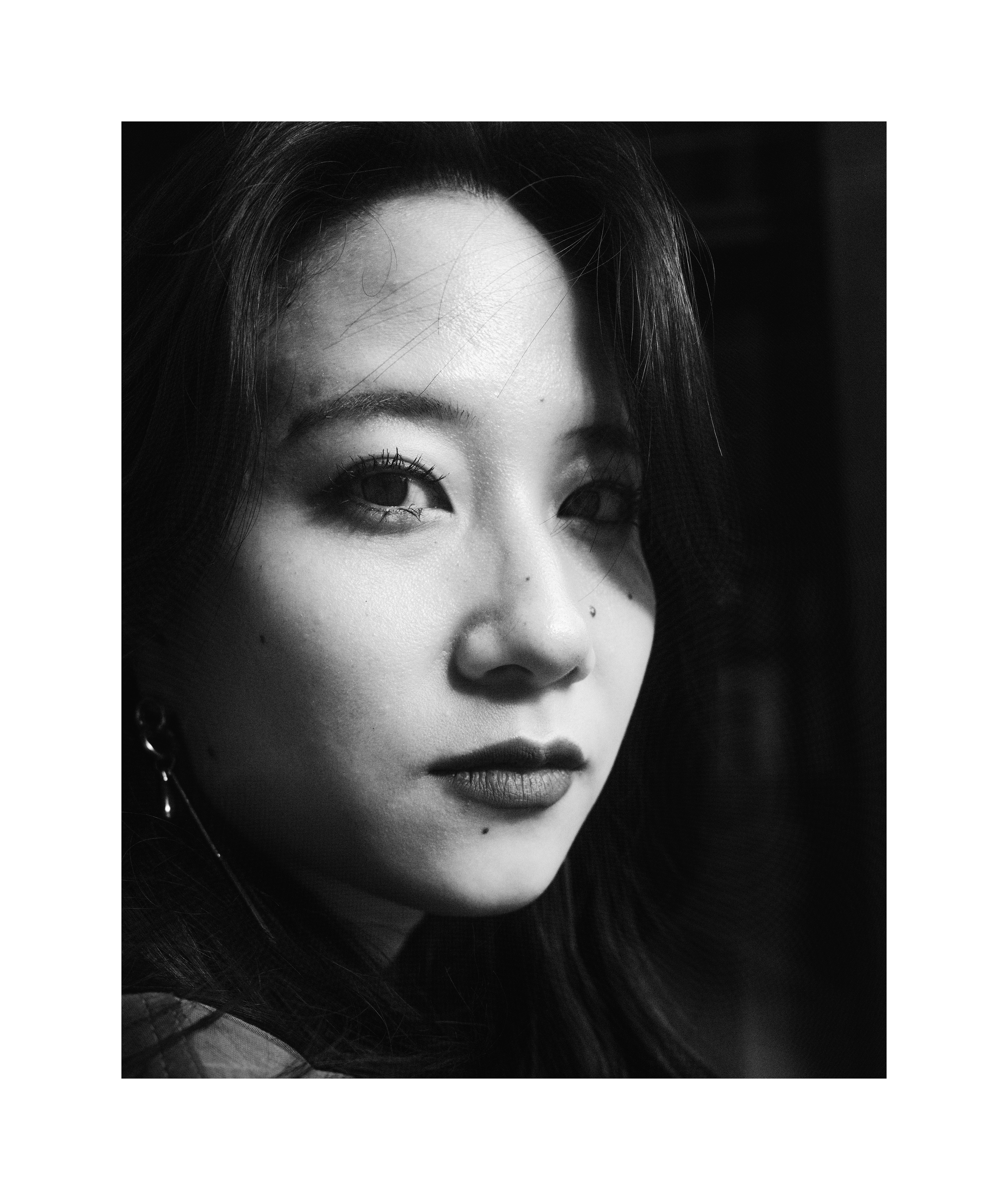 Black and white close-up editorial portrait of Madoka with dramatic light and shadow