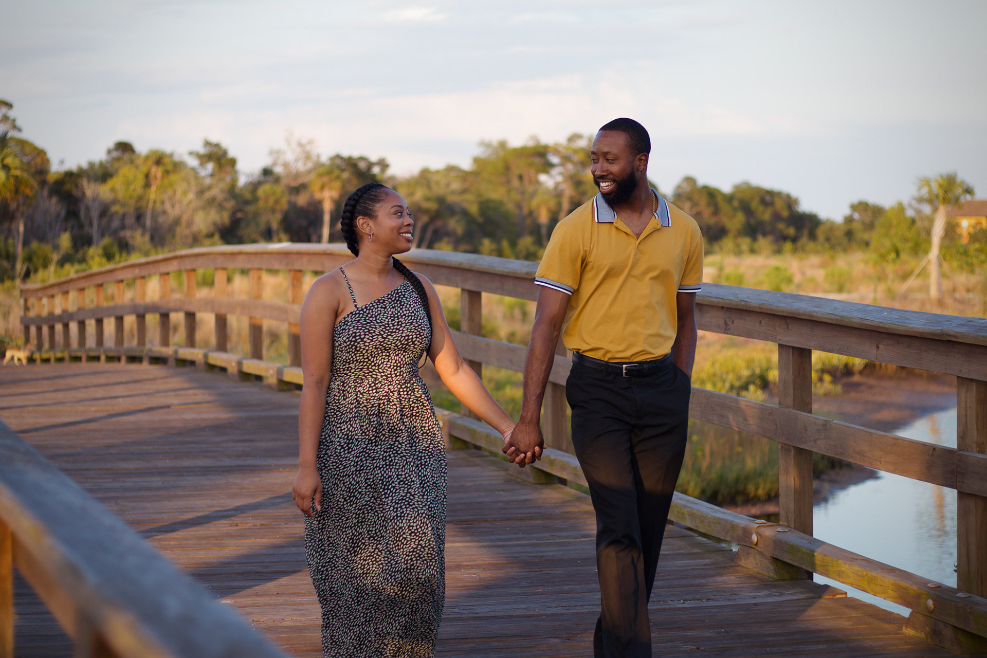 Couple smiling at each other walking down a bridge - Robinson Preserve Couple Photoshoot