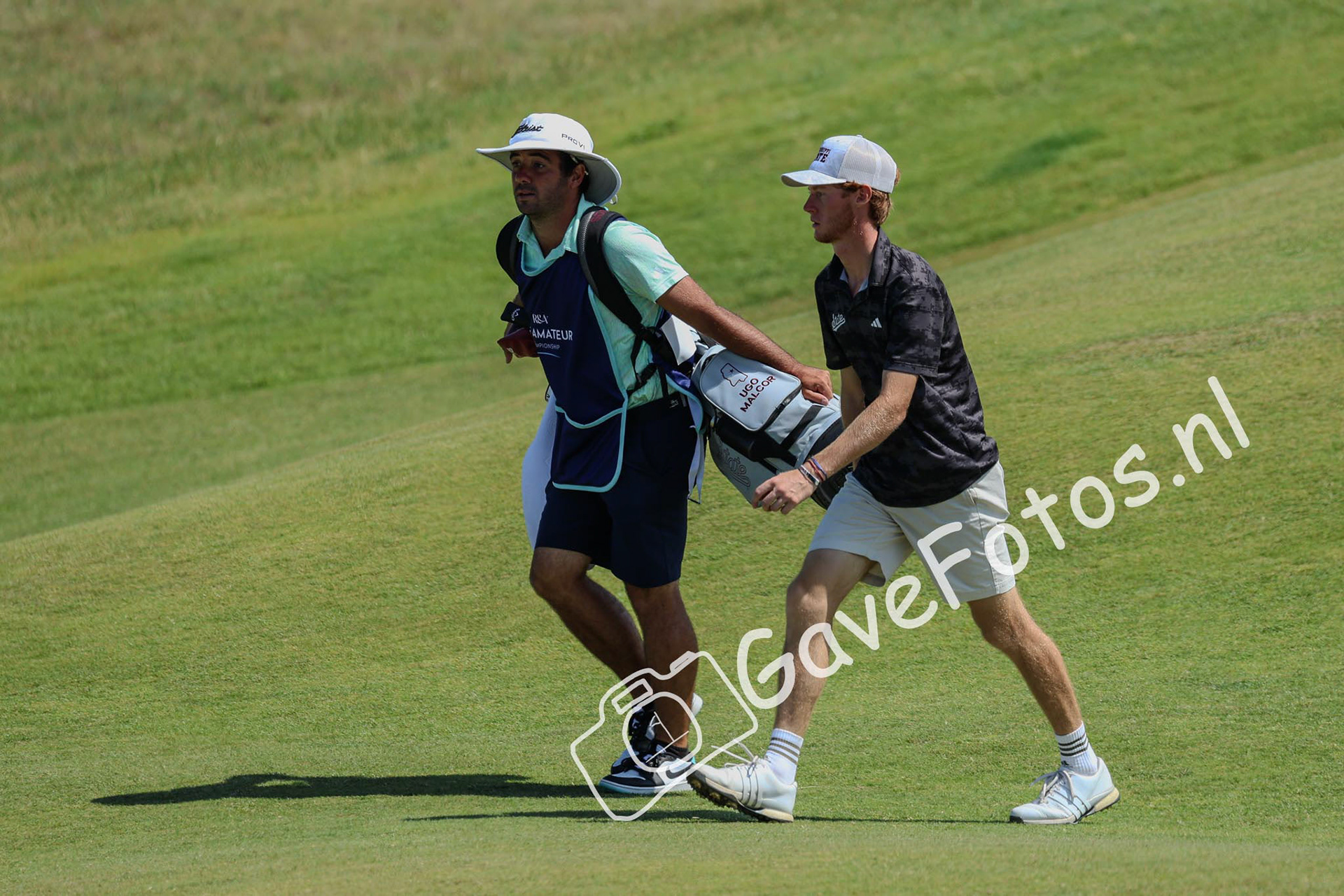Ugo Malor en zijn caddy op weg naar de green van hole 5 op Royal St George